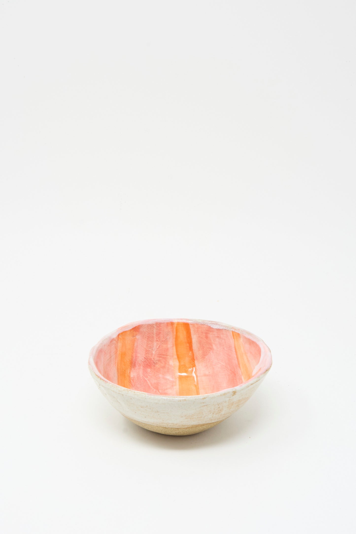 The Shino Takeda Bowl in Orange Stripe is a handmade ceramic piece from New York, featuring a white exterior and an interior with bold orange and red stripes, displayed on a plain white background.