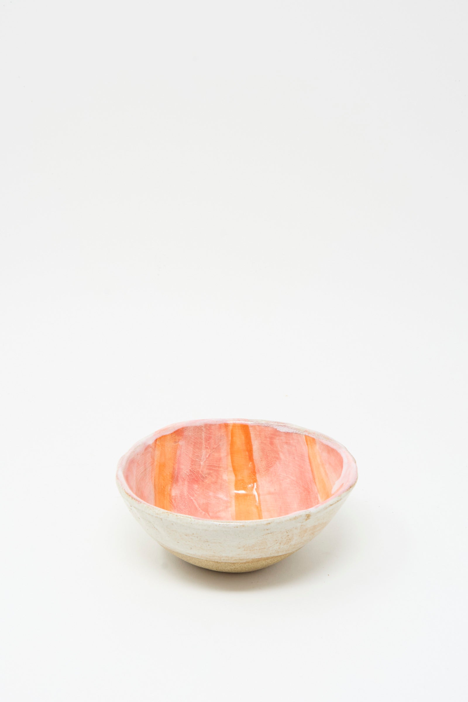 The Shino Takeda Bowl in Orange Stripe is a handmade ceramic piece from New York, featuring a white exterior and an interior with bold orange and red stripes, displayed on a plain white background.