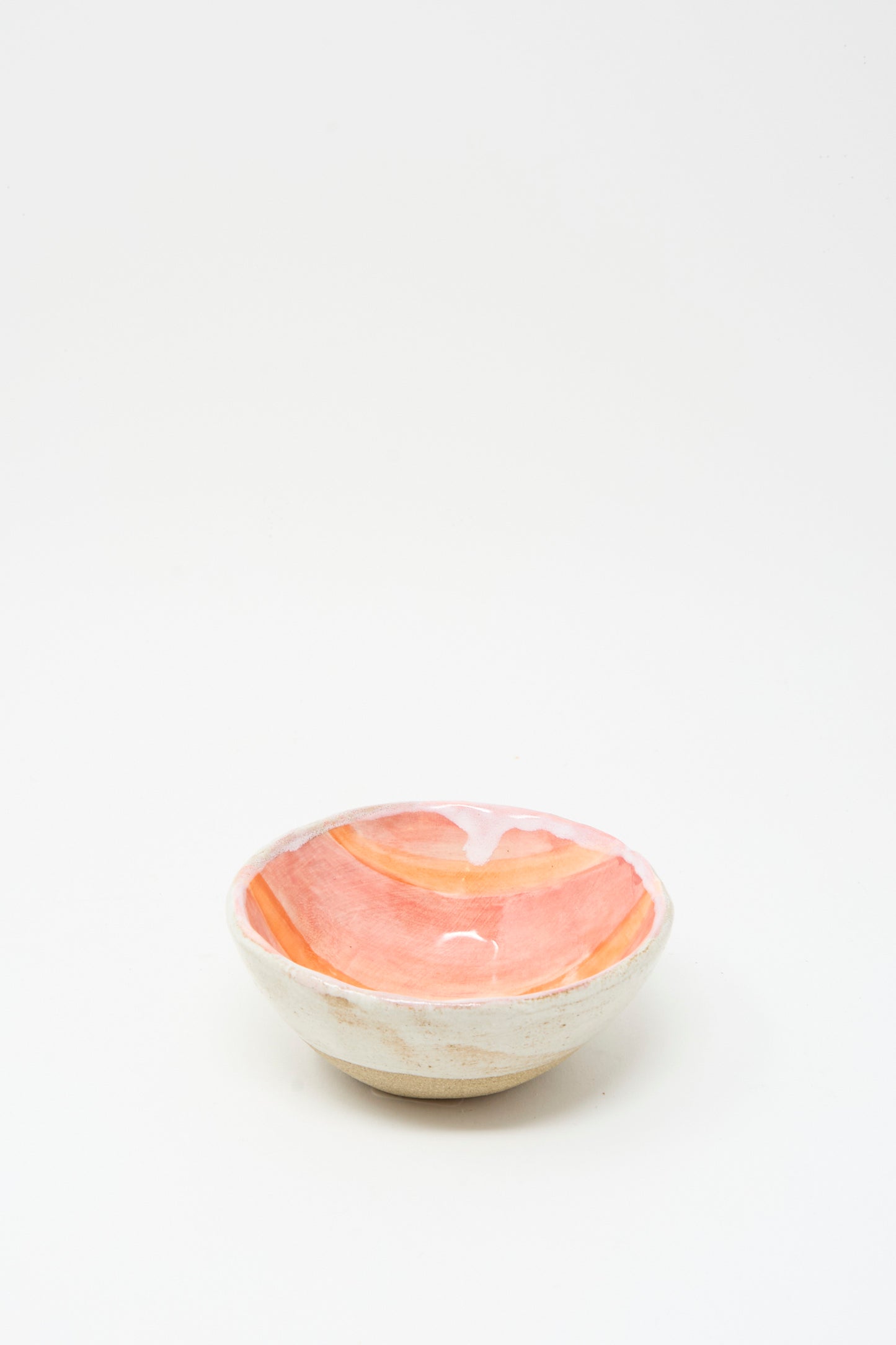 The Bowl in Orange Stripe by Shino Takeda is a small, handmade ceramic bowl from New York, featuring a pink and orange glazed interior against a plain white background.