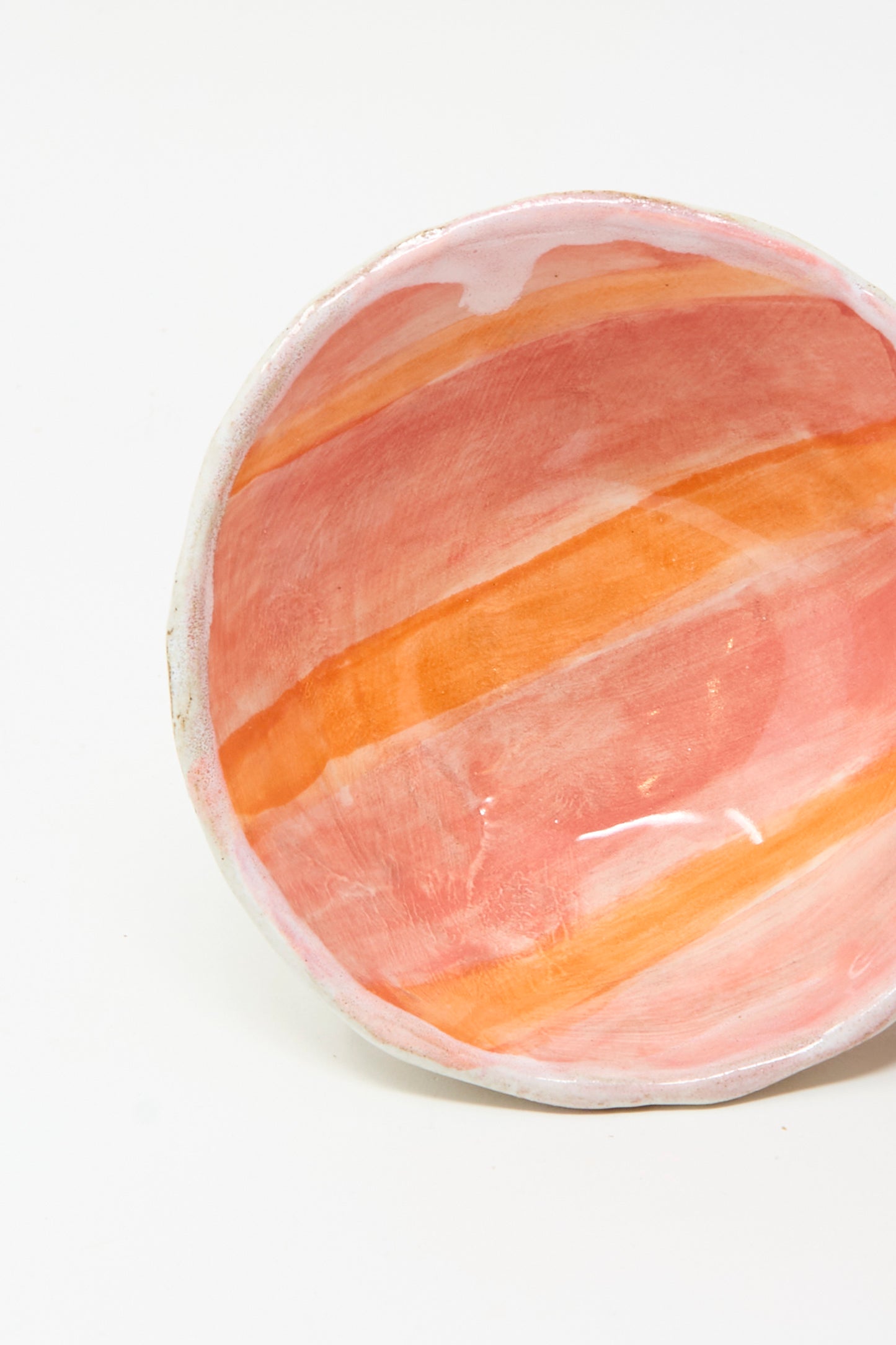 The Shino Takeda Bowl in Orange Stripe is handmade in New York, featuring an irregular rim and a glossy interior with vibrant orange and red stripes, shown here against a white background.