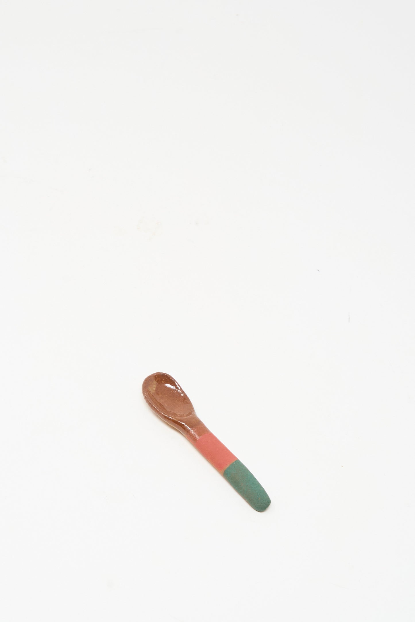 The Condiment Spoon in Green Red by Shino Takeda is a small handmade wooden spoon with a green and red painted handle, shown on a plain white background.