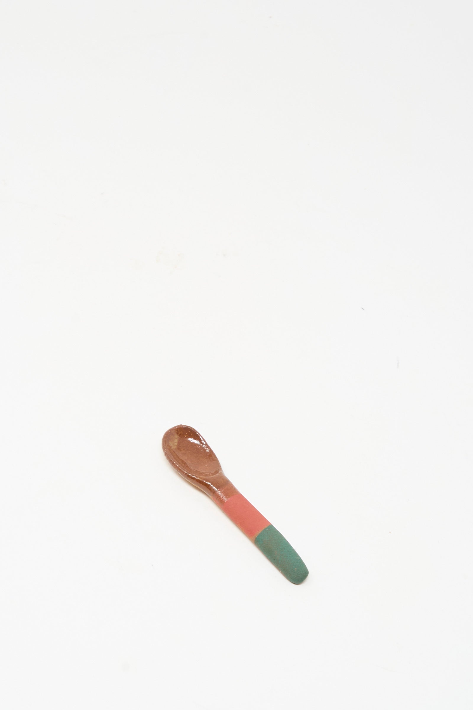 The Condiment Spoon in Green Red by Shino Takeda is a small handmade wooden spoon with a green and red painted handle, shown on a plain white background.