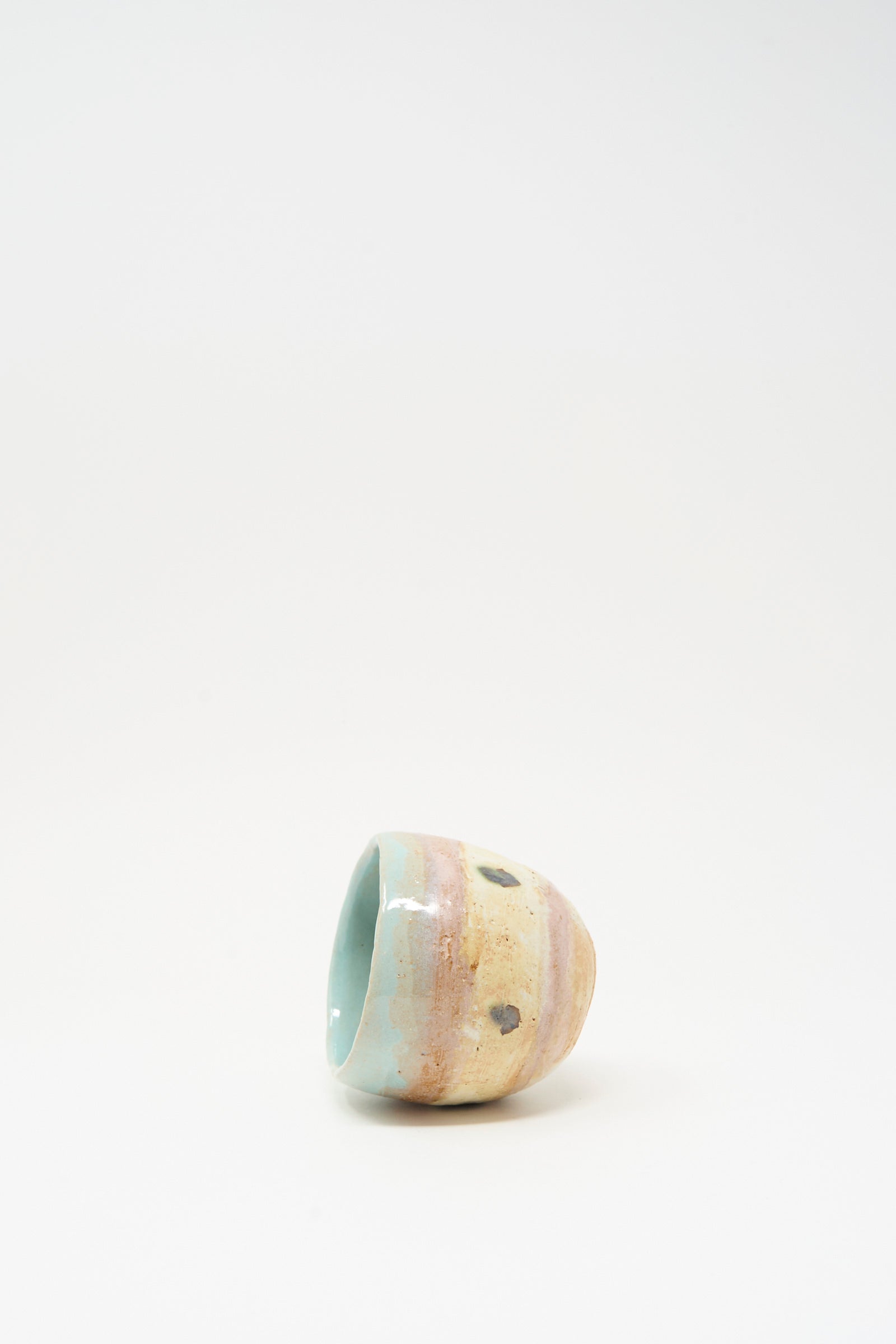 The Cup in Dots II by Shino Takeda is a small, hand-painted ceramic cup featuring a pastel glaze with brown spots, shown lying on its side against a plain white background.
