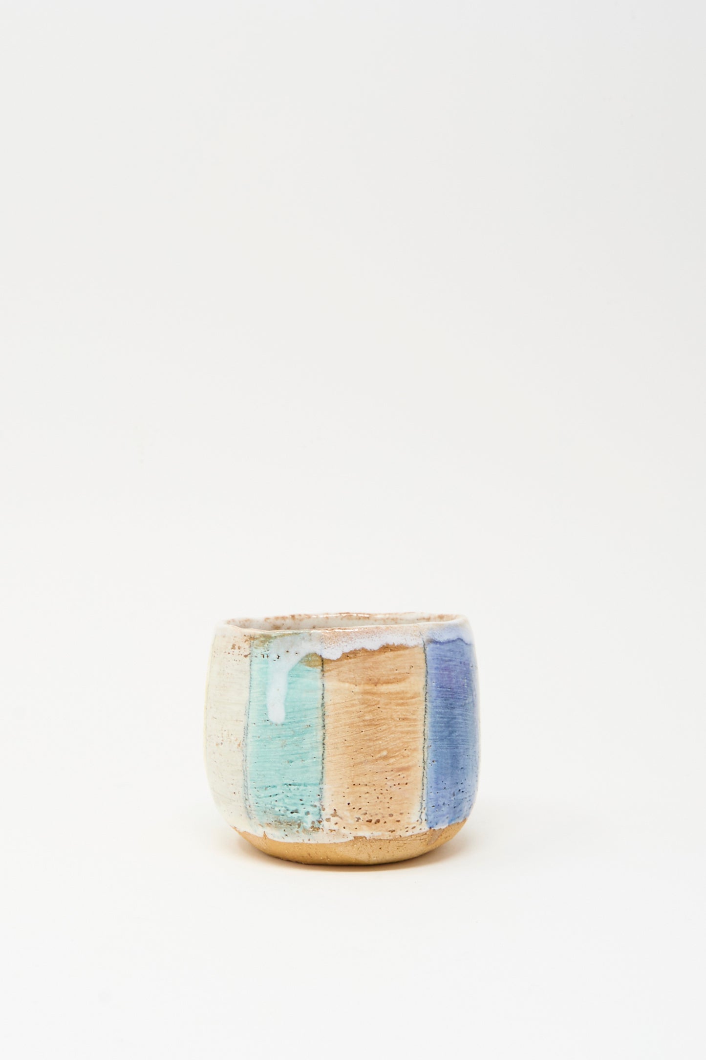The Cup in Stripe by Shino Takeda is a small ceramic cup with a textured surface, hand-painted in vertical pastel stripes of blue, beige, and lavender on white.