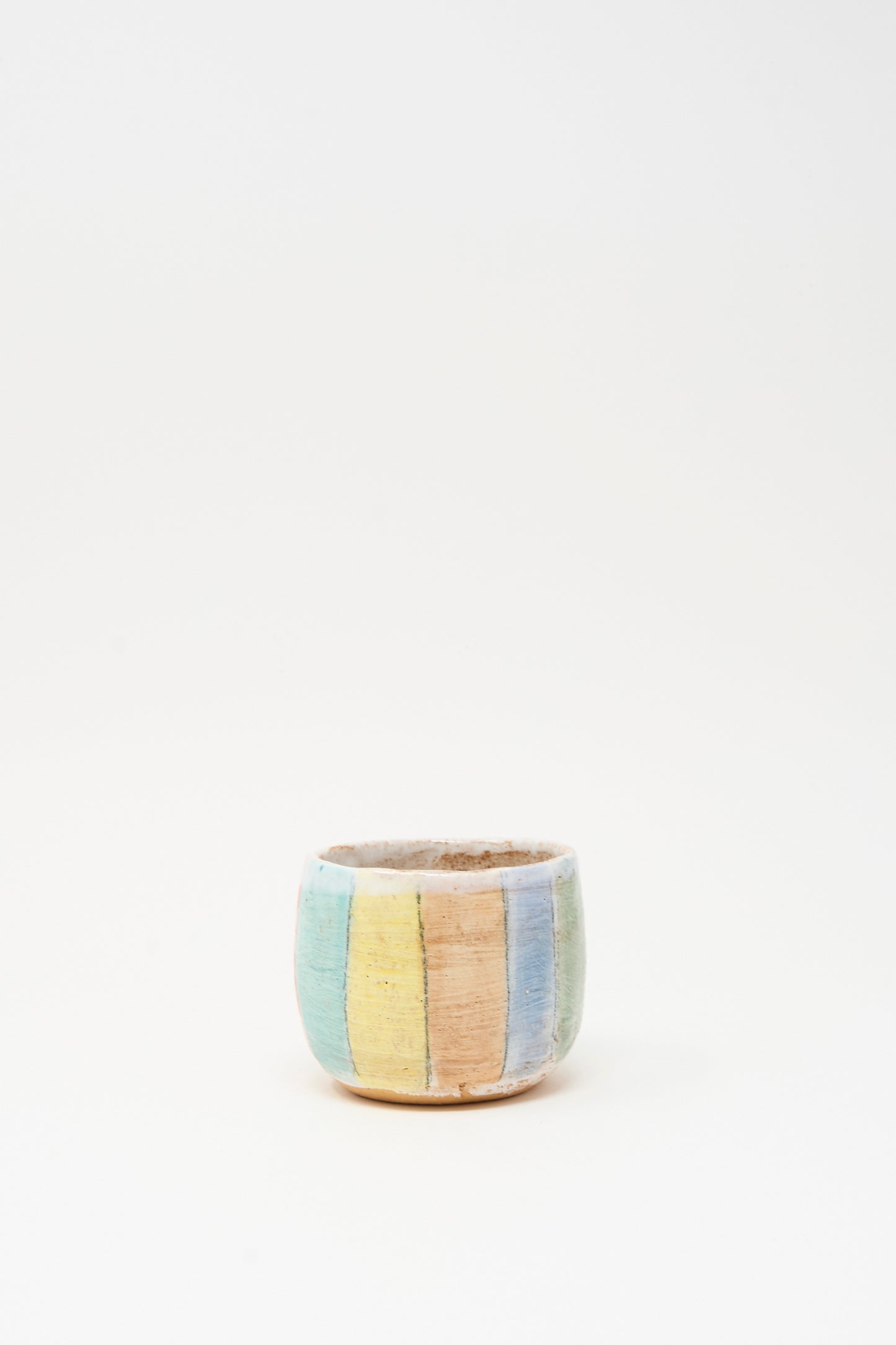 The Cup in Stripe I by Shino Takeda is a small hand-painted ceramic cup with pastel vertical stripes, made in New York, shown on a plain white background.