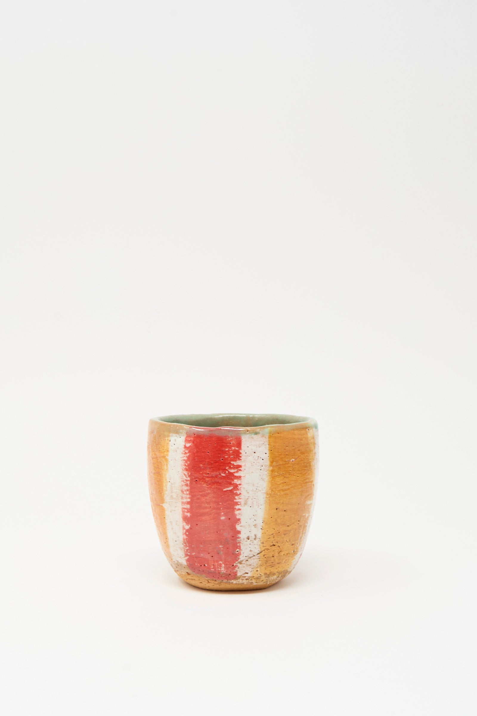 The Shino Takeda Cup in Stripe II is a small hand-painted ceramic cup featuring orange, white, and red vertical stripes on a plain white background.
