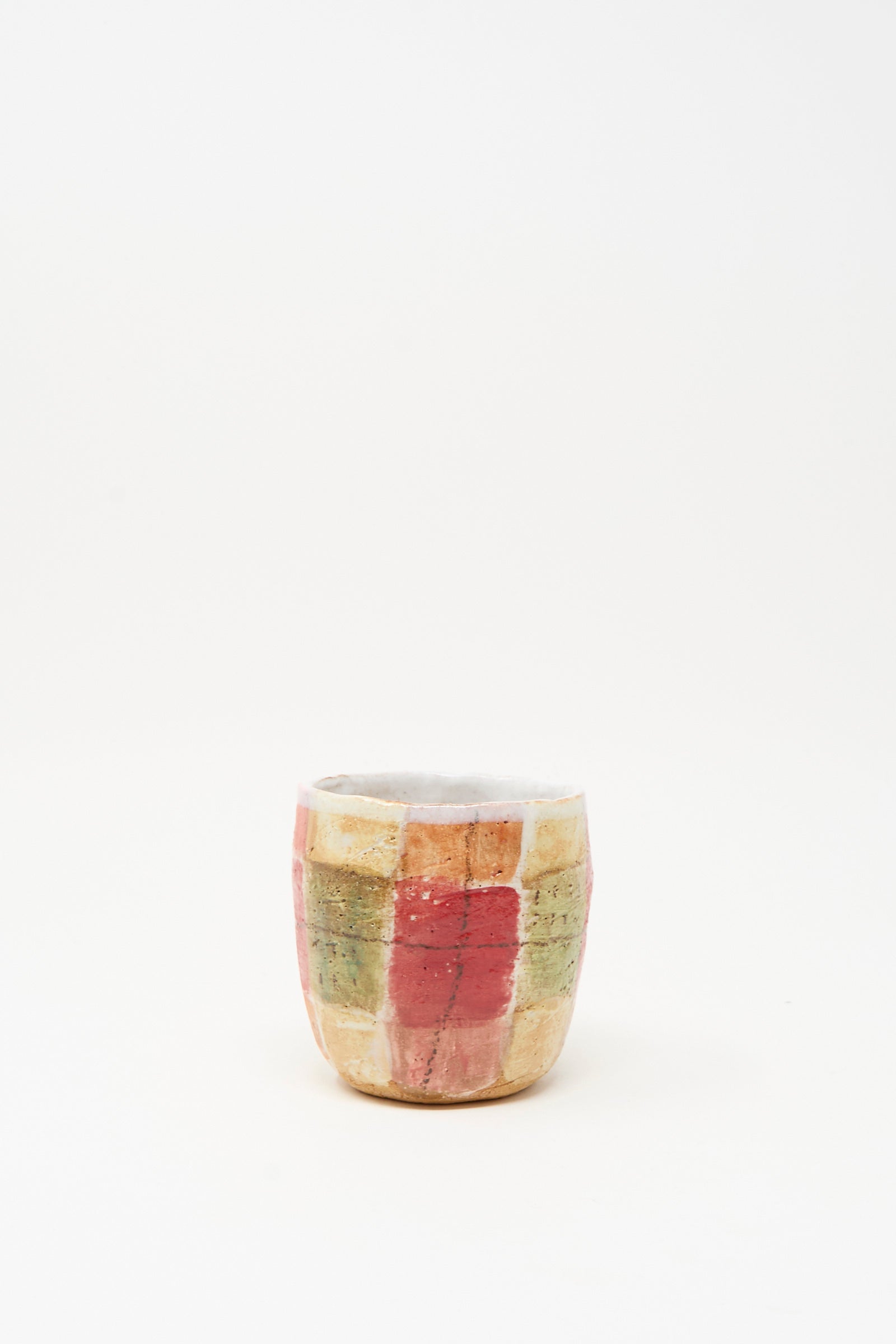 The Shino Takeda "Cup in Red Plaid I" is a hand-painted ceramic cup, handmade in New York with a red, yellow, and green grid pattern, shown against a plain white background.