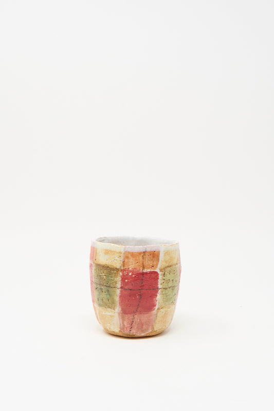 The Shino Takeda "Cup in Red Plaid I" is a hand-painted ceramic cup, handmade in New York with a red, yellow, and green grid pattern, shown against a plain white background.