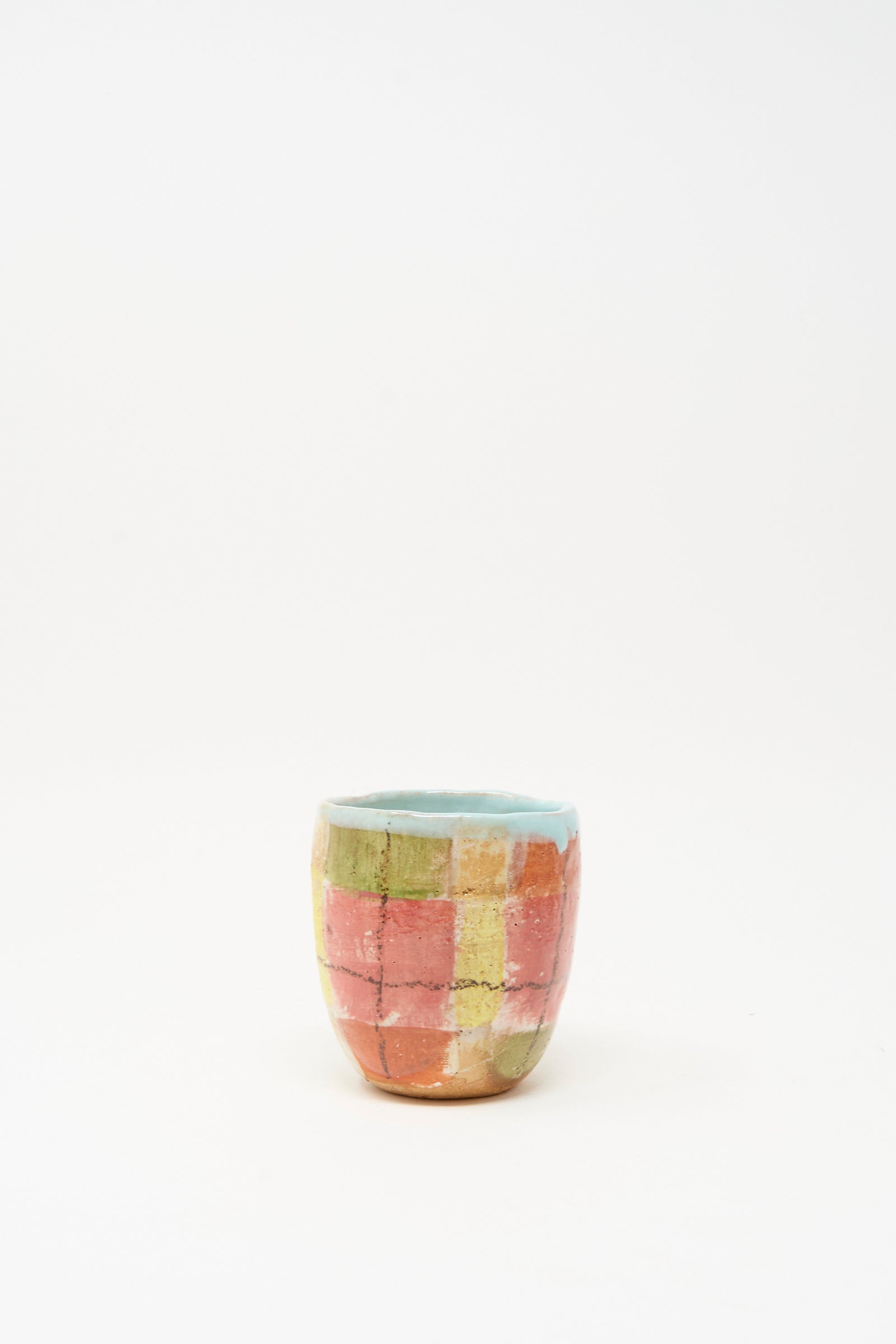 The Shino Takeda Cup in Red Plaid II is a small, handmade ceramic cup from New York, featuring a hand-painted red checkered pattern and light blue interior, shown against a plain white background.