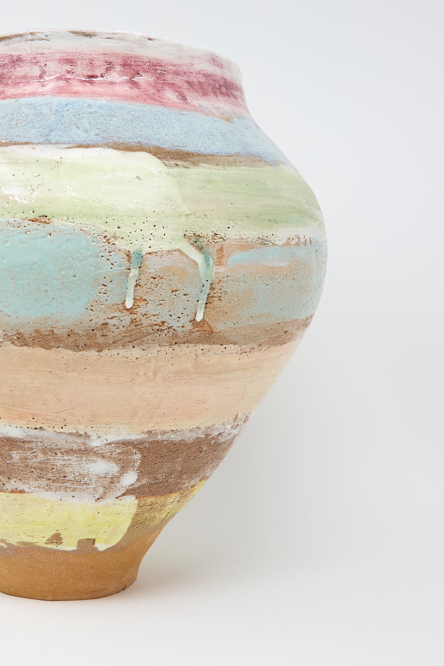 The Large Vase in Pastel Stripe by Shino Takeda features a rounded shape and hand-painted details, displaying layered, earthy colors such as blue, green, pink, and yellow with visible paint drips.