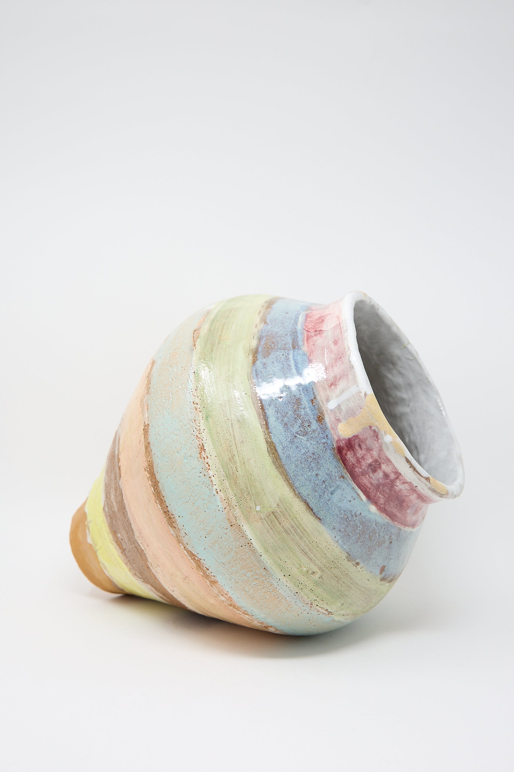 The Large Vase in Pastel Stripe by Shino Takeda is tilted on a white background, showcasing its hand-painted, colorful pastel horizontal stripes.