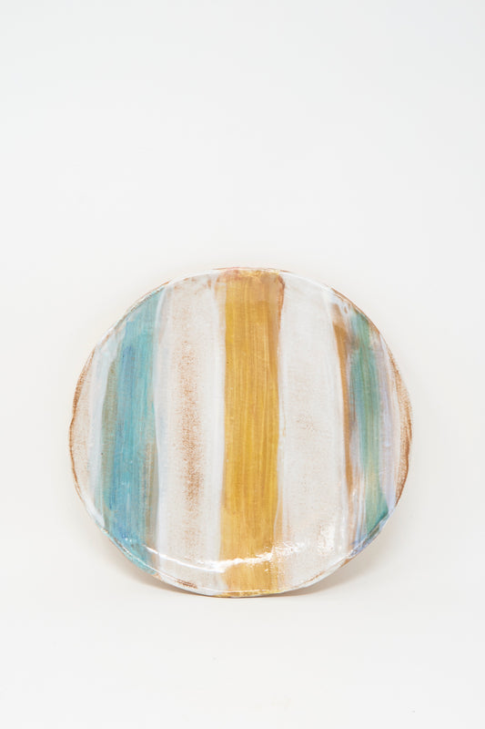 The Shino Takeda Serving Plate in Blue Yellow Stripe is a round, handmade ceramic piece with vertical blue, yellow, and white stripes and a subtly irregular rim, shown against a plain white background.