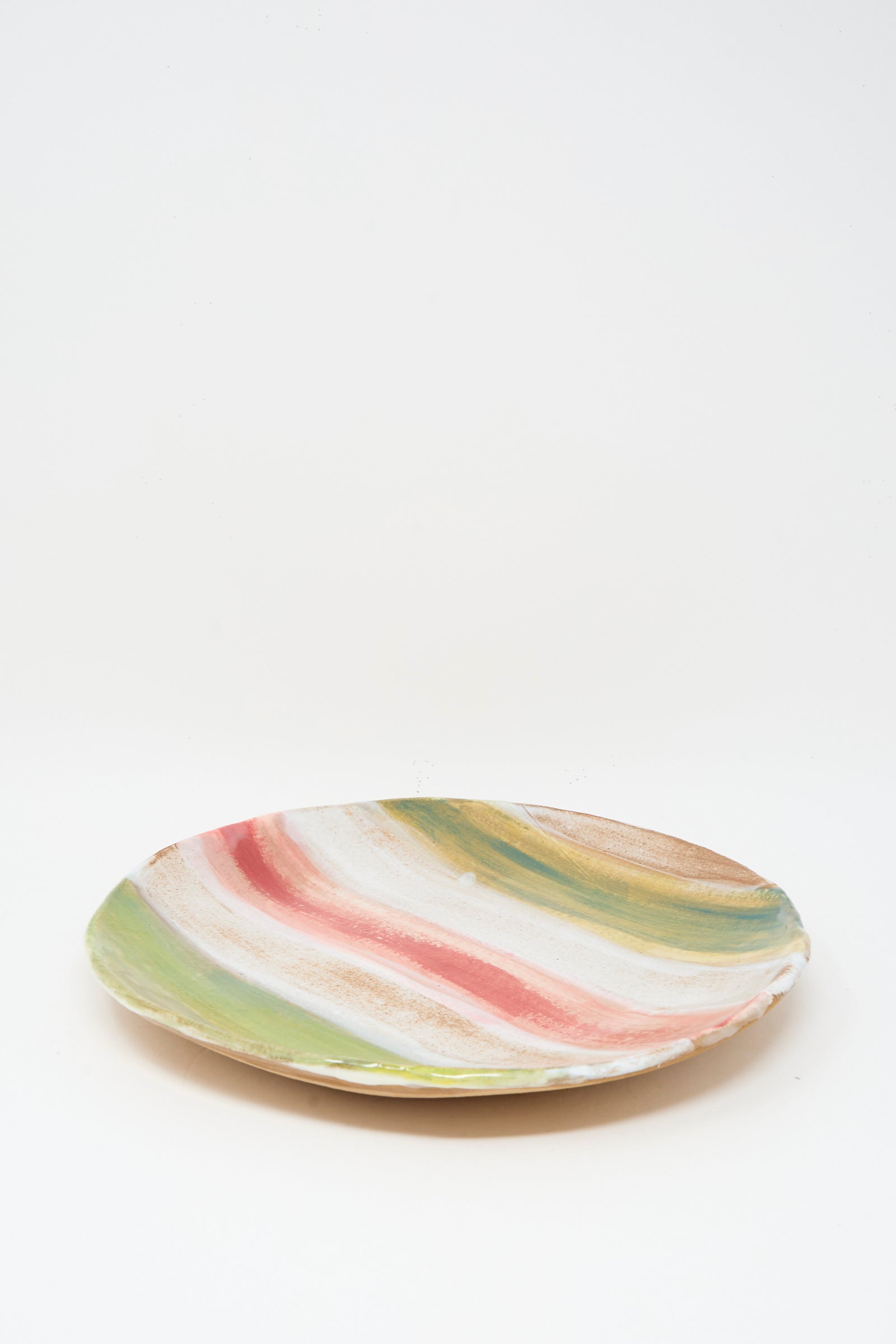 The Shino Takeda Serving Plate in Red Green Stripe is a handmade ceramic plate with wavy green, red, and beige stripes on a white background.