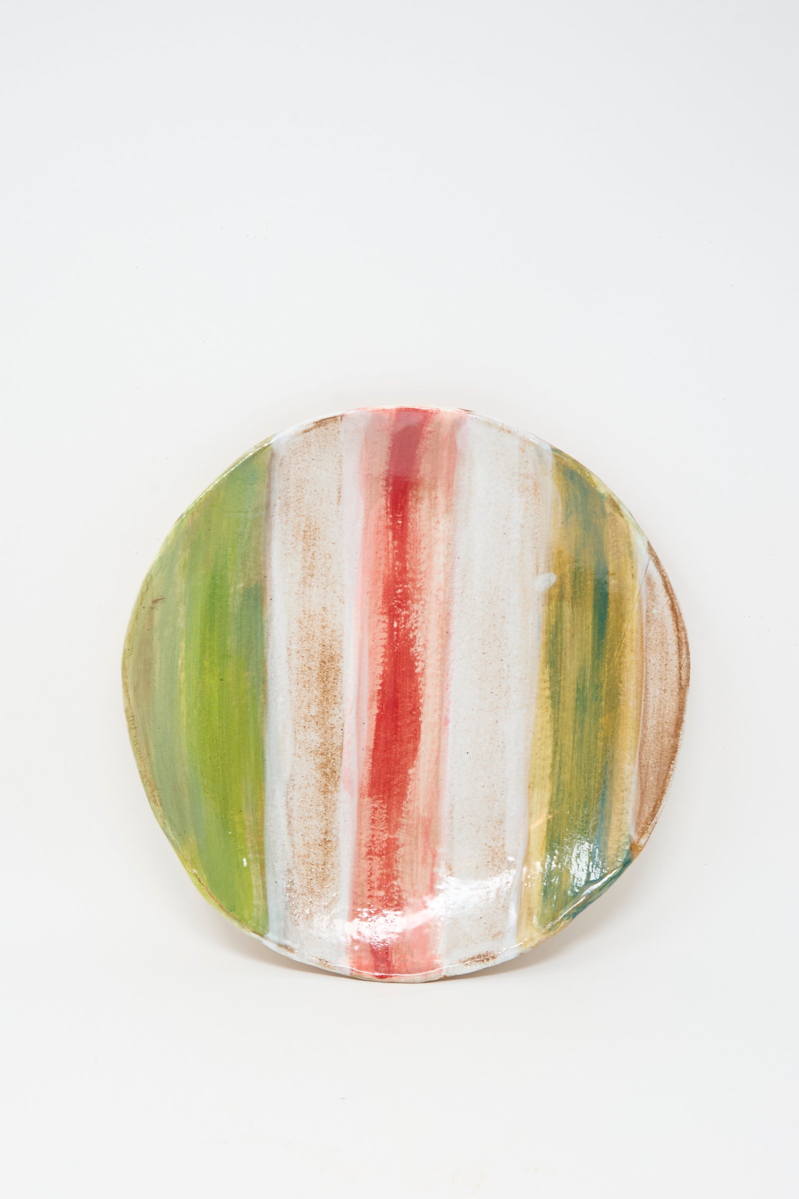 The Serving Plate in Red Green Stripe by Shino Takeda features handmade ceramic craftsmanship with vertical stripes in green, red, and brown on a crisp white background.