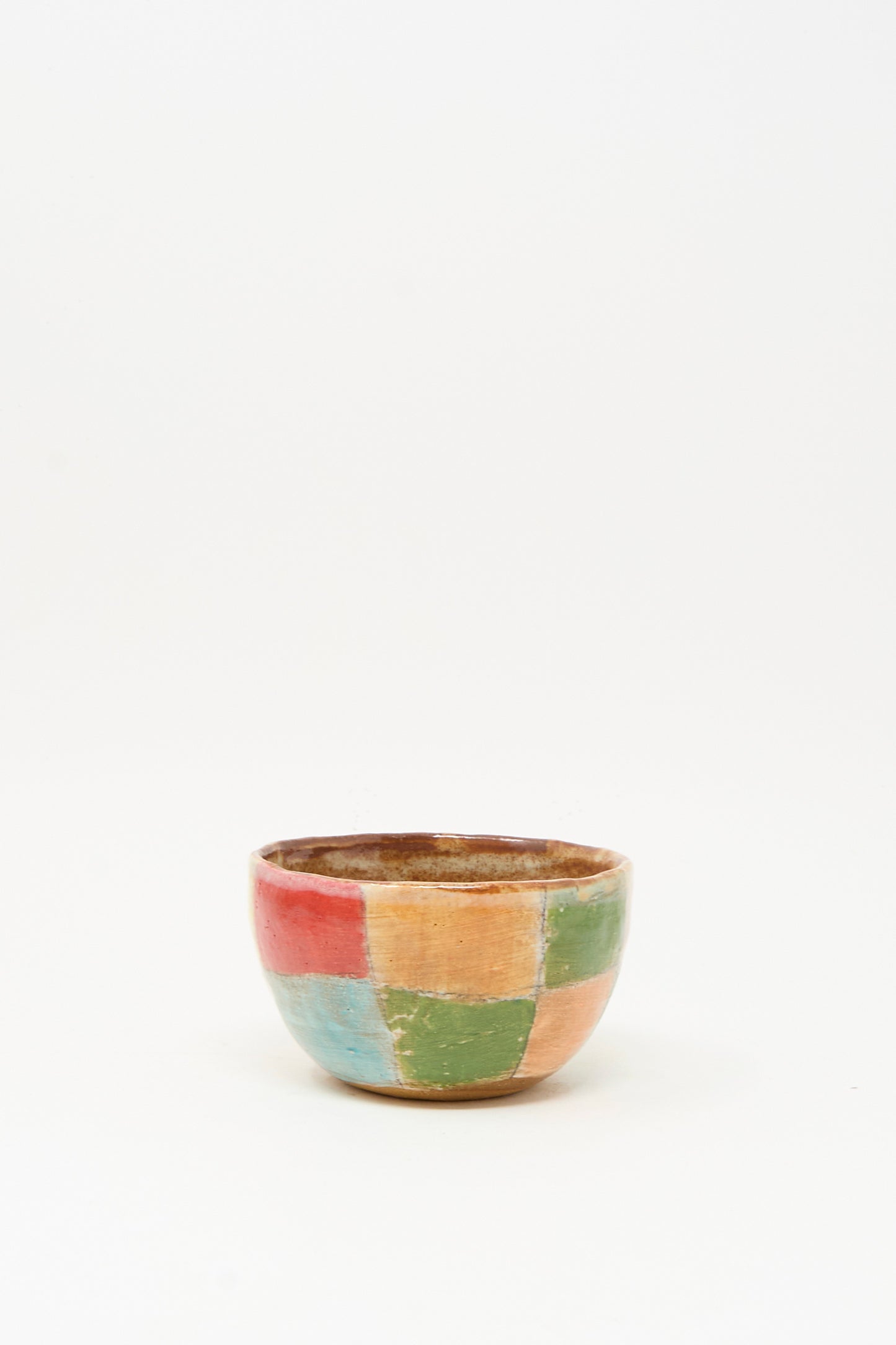 The Small Bowl in Check Multi I by Shino Takeda is a handmade ceramic bowl featuring a vibrant patchwork of red, green, orange, and blue squares on a plain white background.
