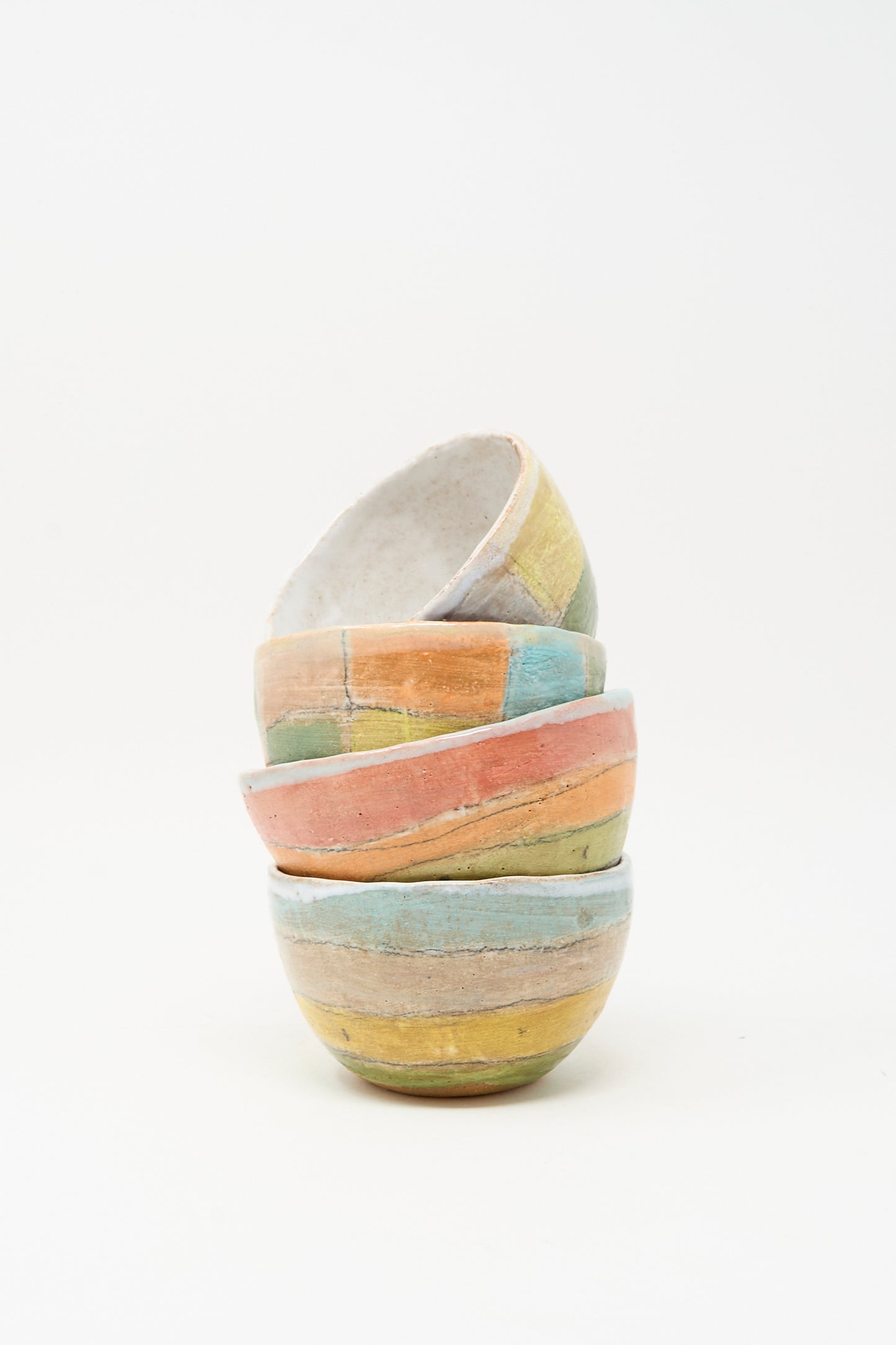 Four Small Bowl in Check Multi I by Shino Takeda are stacked unevenly against a plain white background, each bowl showcasing unique hand-painted ceramic details and colorful handmade design.