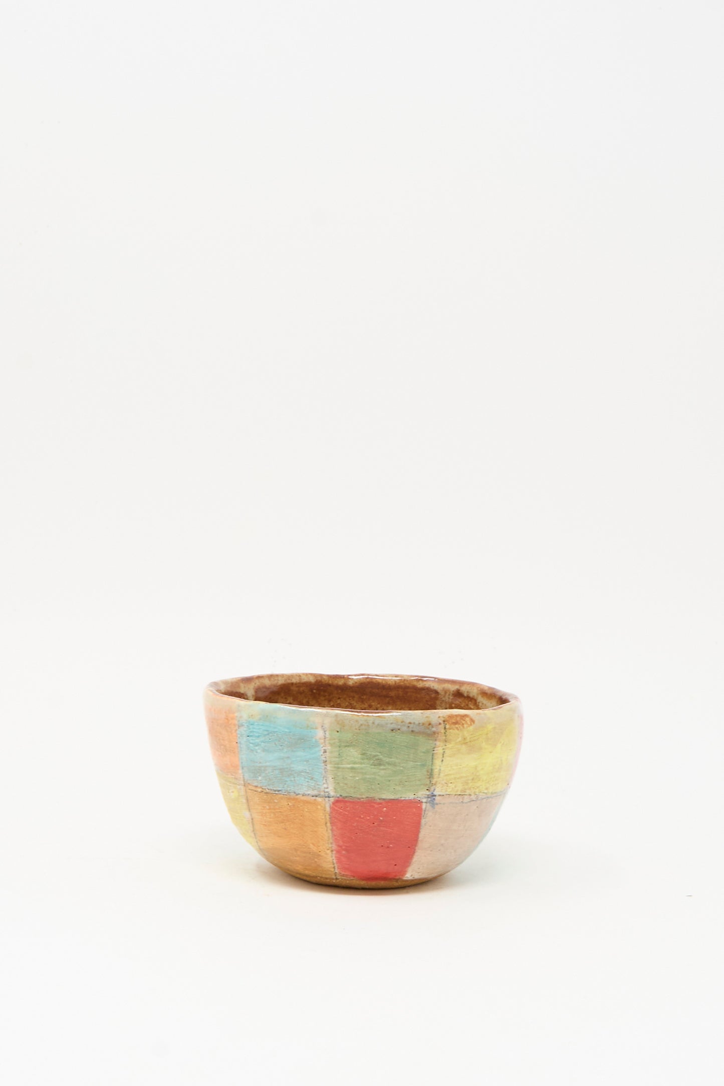 The Small Bowl in Check Multi I by Shino Takeda is a handmade ceramic piece featuring a hand-painted pastel checkered pattern in blue, yellow, green, and red, shown on a plain white background.