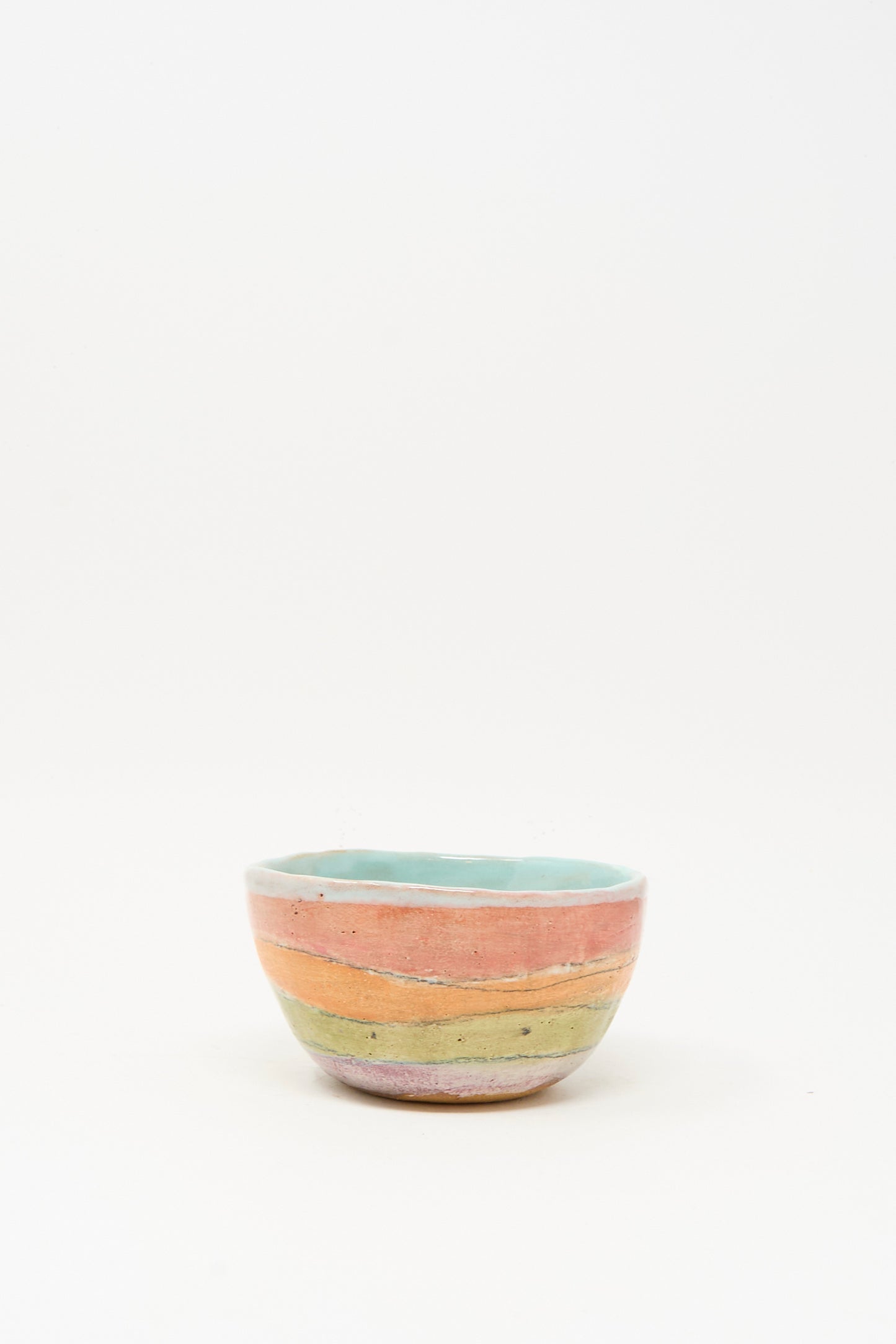 The Small Bowl in Stripe I by Shino Takeda is a handmade ceramic bowl with pastel pink, orange, and green stripes and a light blue interior, crafted in New York and shown on a plain white background.