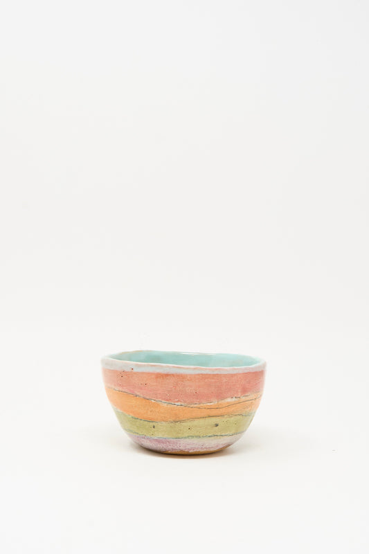 The Small Bowl in Stripe I by Shino Takeda is a handmade ceramic bowl with pastel pink, orange, and green stripes and a light blue interior, crafted in New York and shown on a plain white background.