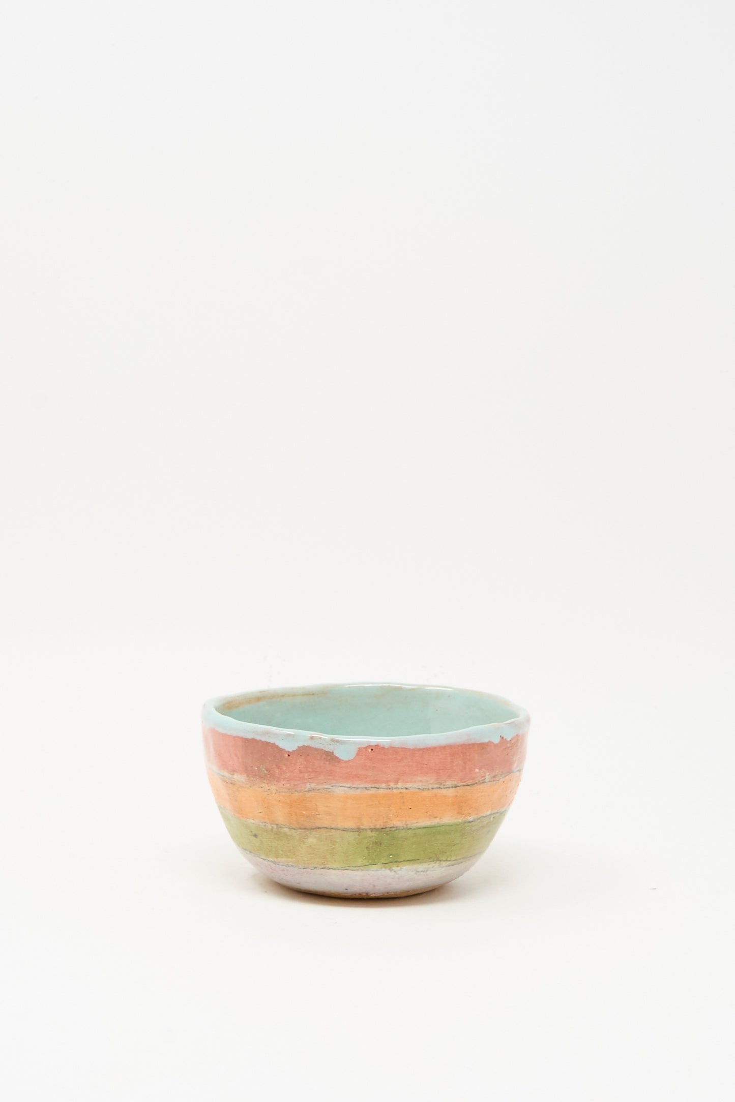 The Small Bowl in Stripe I by Shino Takeda, handmade in New York and hand-painted with green, orange, and blue stripes, is displayed on a plain white background.