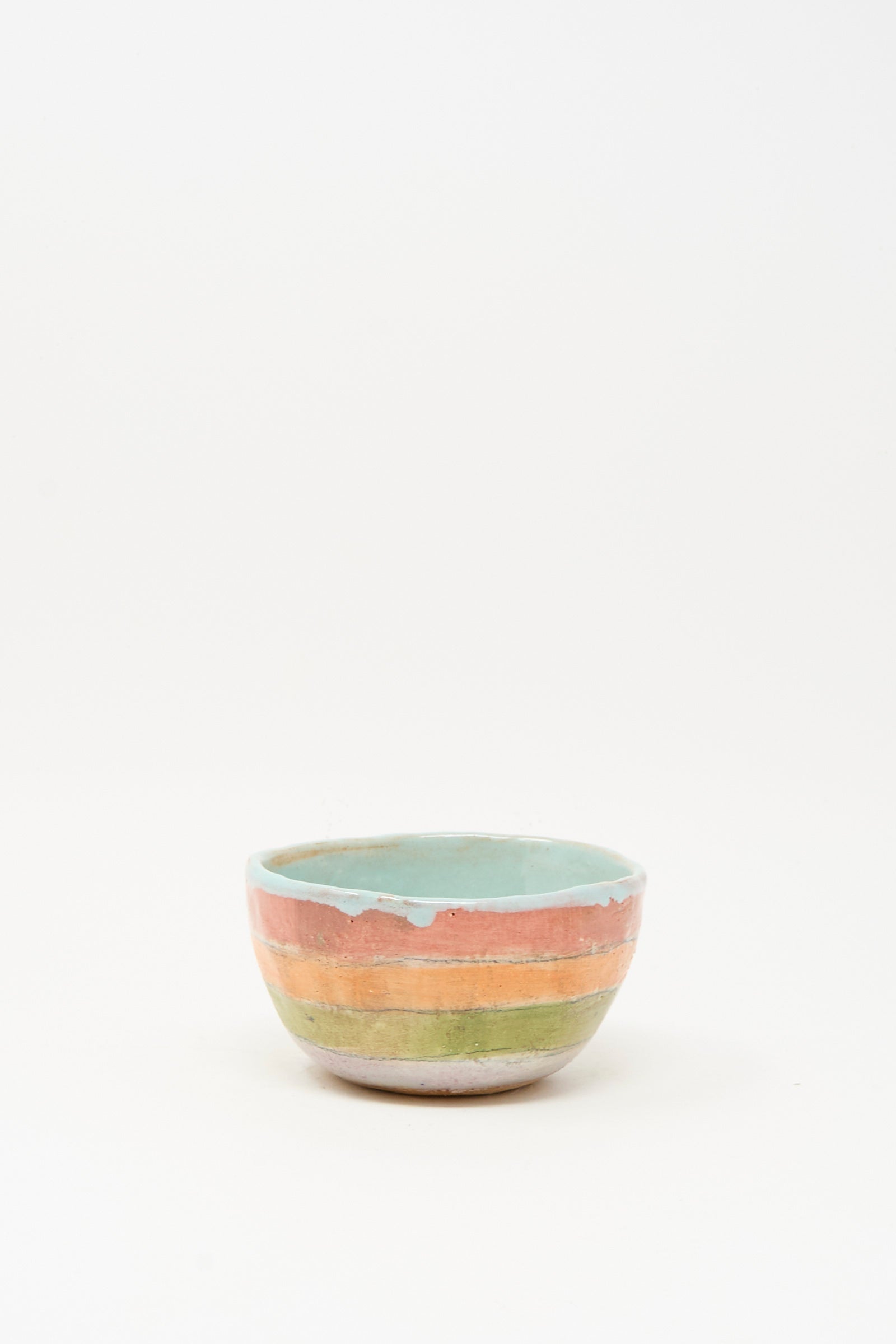The Small Bowl in Stripe I by Shino Takeda, handmade in New York and hand-painted with green, orange, and blue stripes, is displayed on a plain white background.