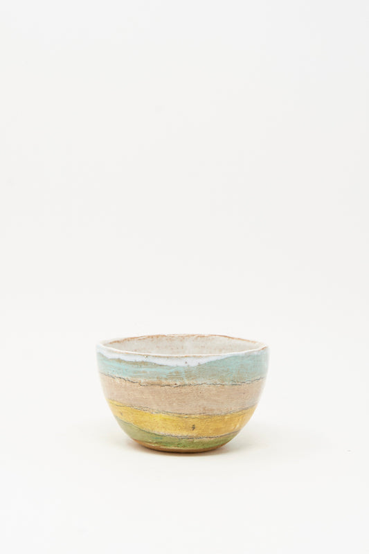 The Small Bowl in Stripe II by Shino Takeda is a handmade ceramic bowl from New York, featuring horizontal pastel blue, beige, yellow, and green stripes, displayed on a plain white background.