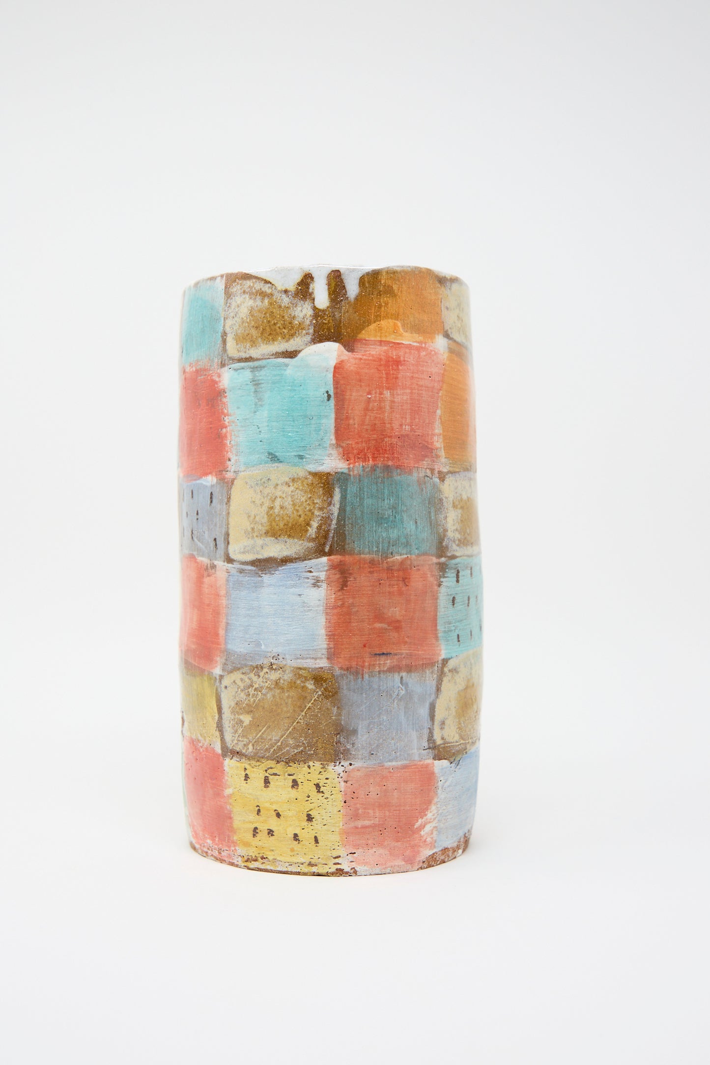 The Vase in Pastel Checker by Shino Takeda features a cylindrical clay form with hand-painted blocks of pastel colors, such as blue, red, orange, and yellow.