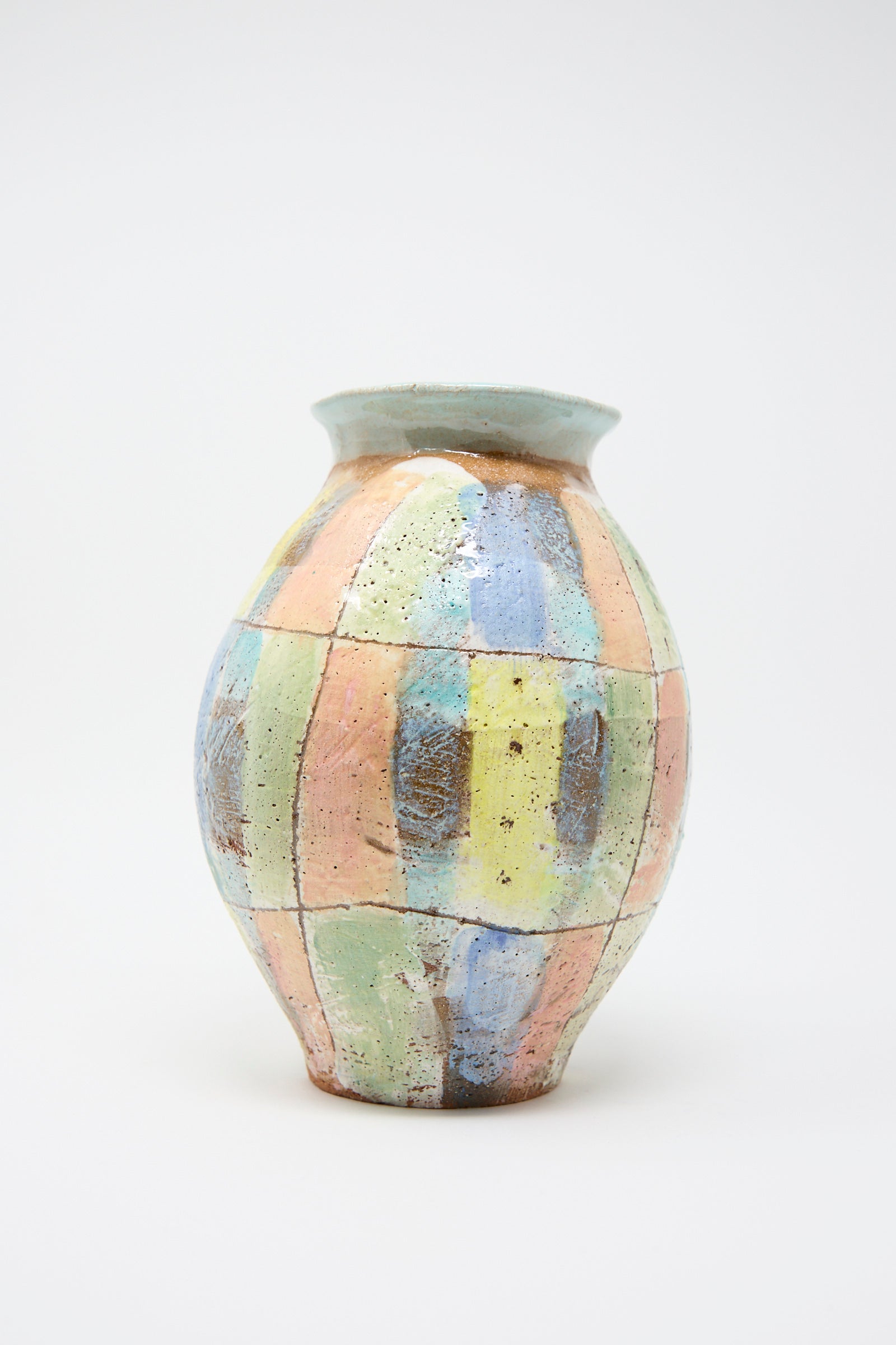 The Shino Takeda "Vase in Pastel Plaid with Blue" is a hand-built clay vase showcasing a patchwork pattern in pastel shades of blue, yellow, pink, and green on a simple white background.