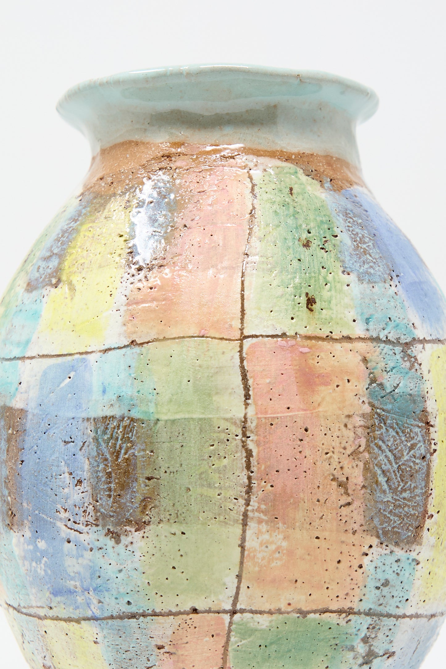 A close up of the hand-crafted vase from Shino Takeda, named "Vase in Pastel Plaid with Blue," features a pastel plaid pattern in shades of blue, green, pink, and yellow set against a neutral background.