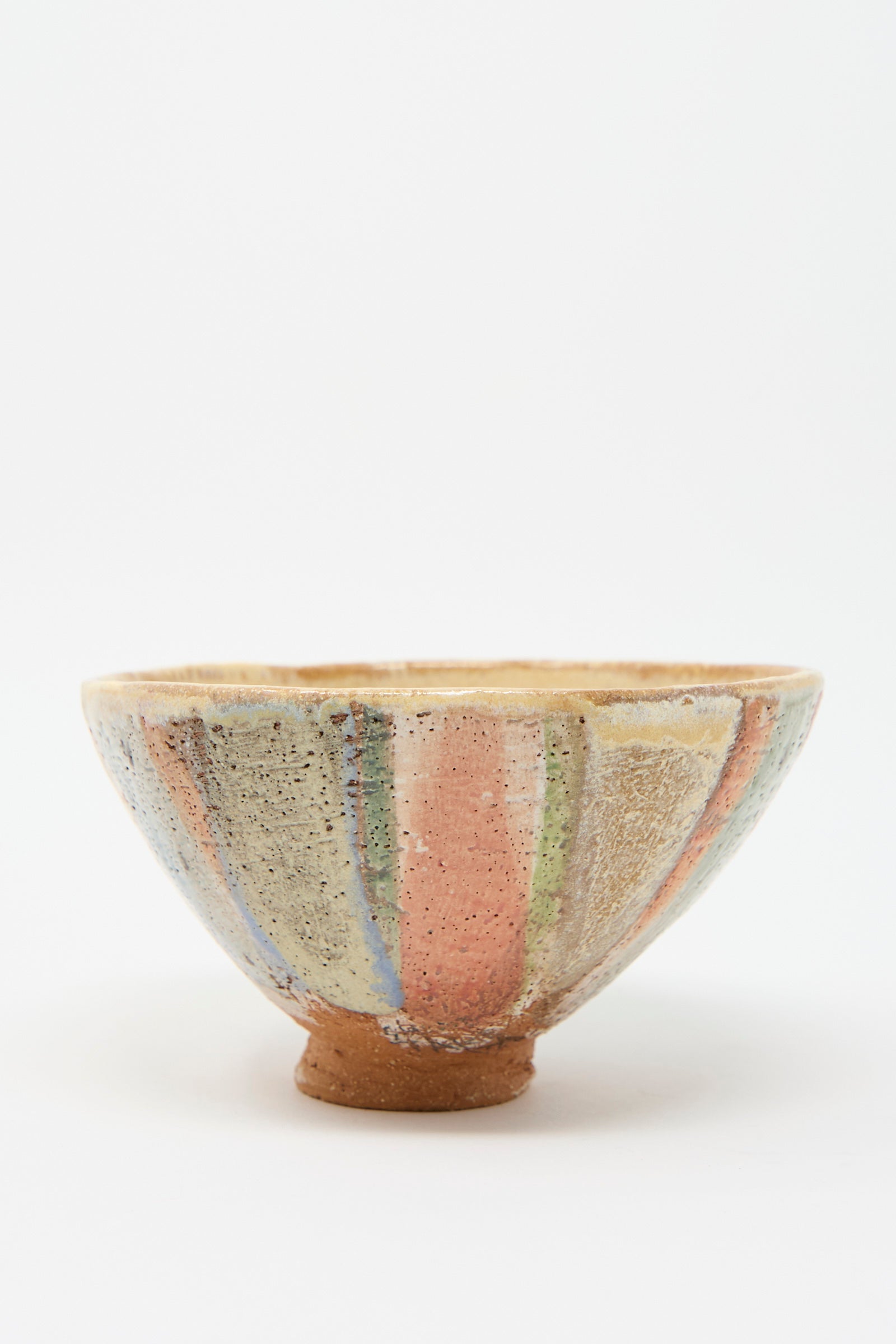 Introducing the Footed Bowl in Pastel Stripe by Shino Takeda: This meticulously handcrafted ceramic bowl features a rustic finish, adorned with vertical stripes in serene earthy tones of beige, orange, green, and blue.