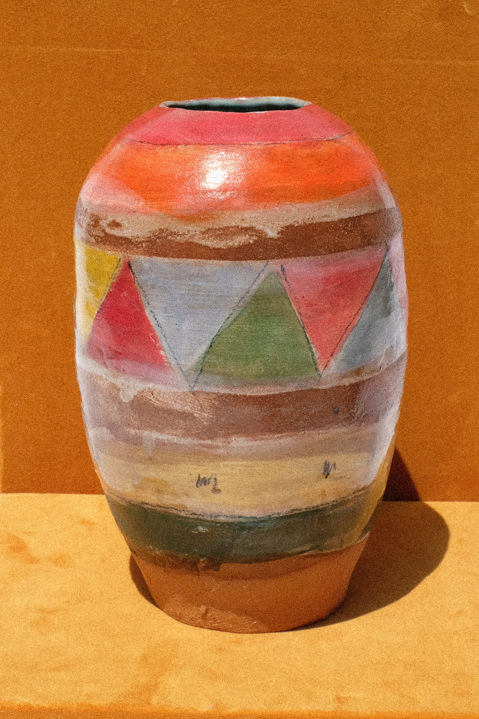 A still image of Shino Takeda's Triangle Vase in Multi against oragne velvet. 