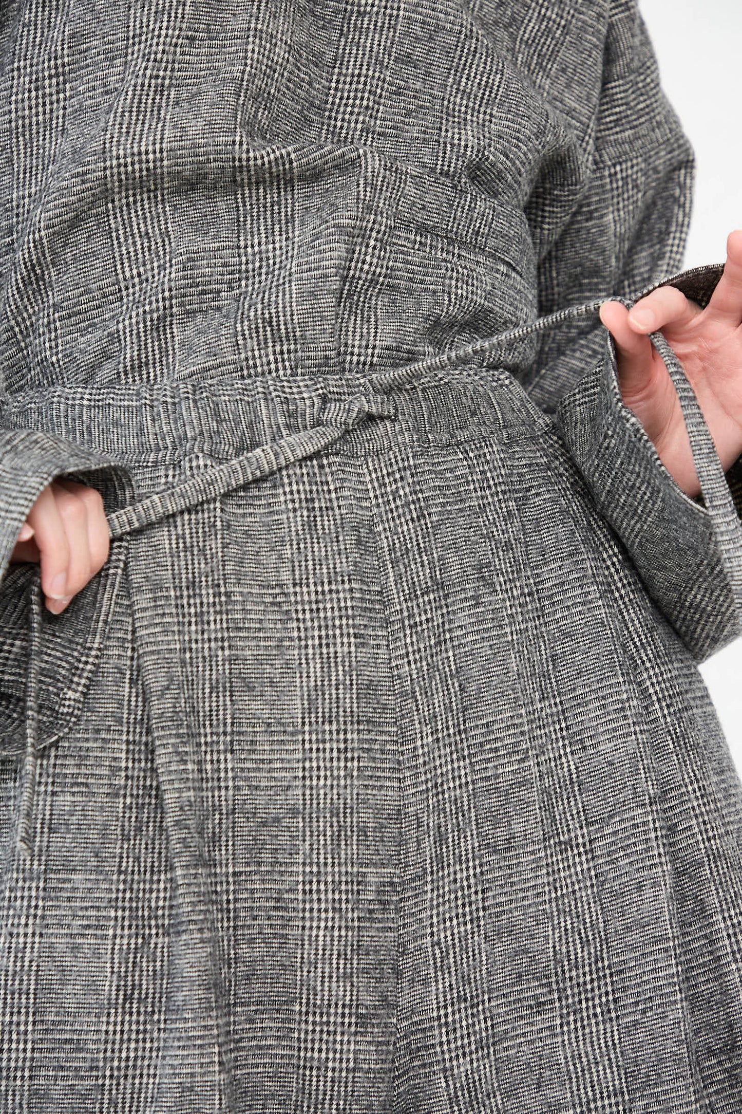 Close-up of a person tying the belt of a Sofie D'Hoore Cotton Wool Washed Palau Pant in Mid Grey.