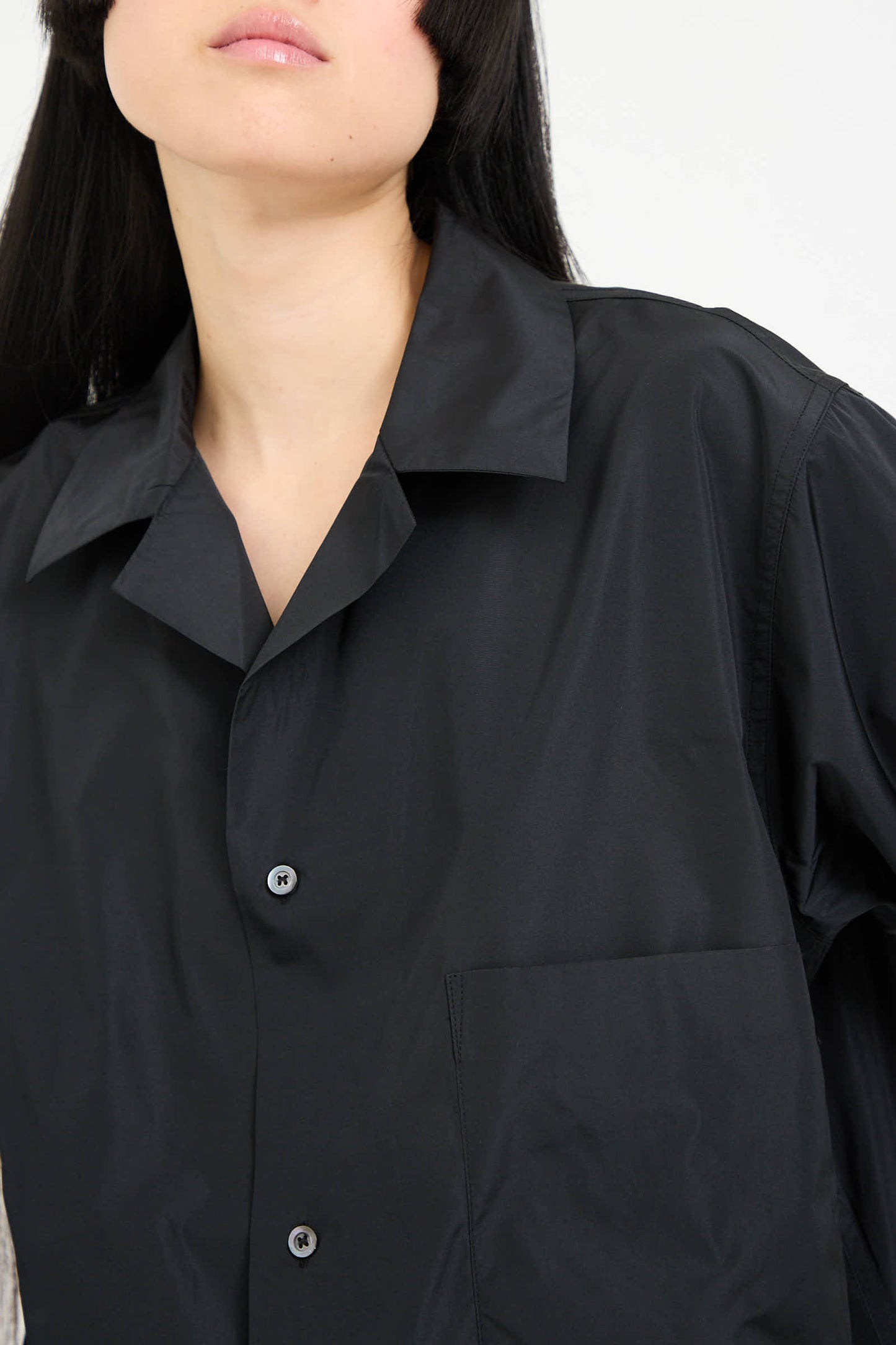 Individual wearing a Sofie D'Hoore Taffeta Barry Shirt with Patch Pocket in Black, showcased from shoulders to mid-torso.