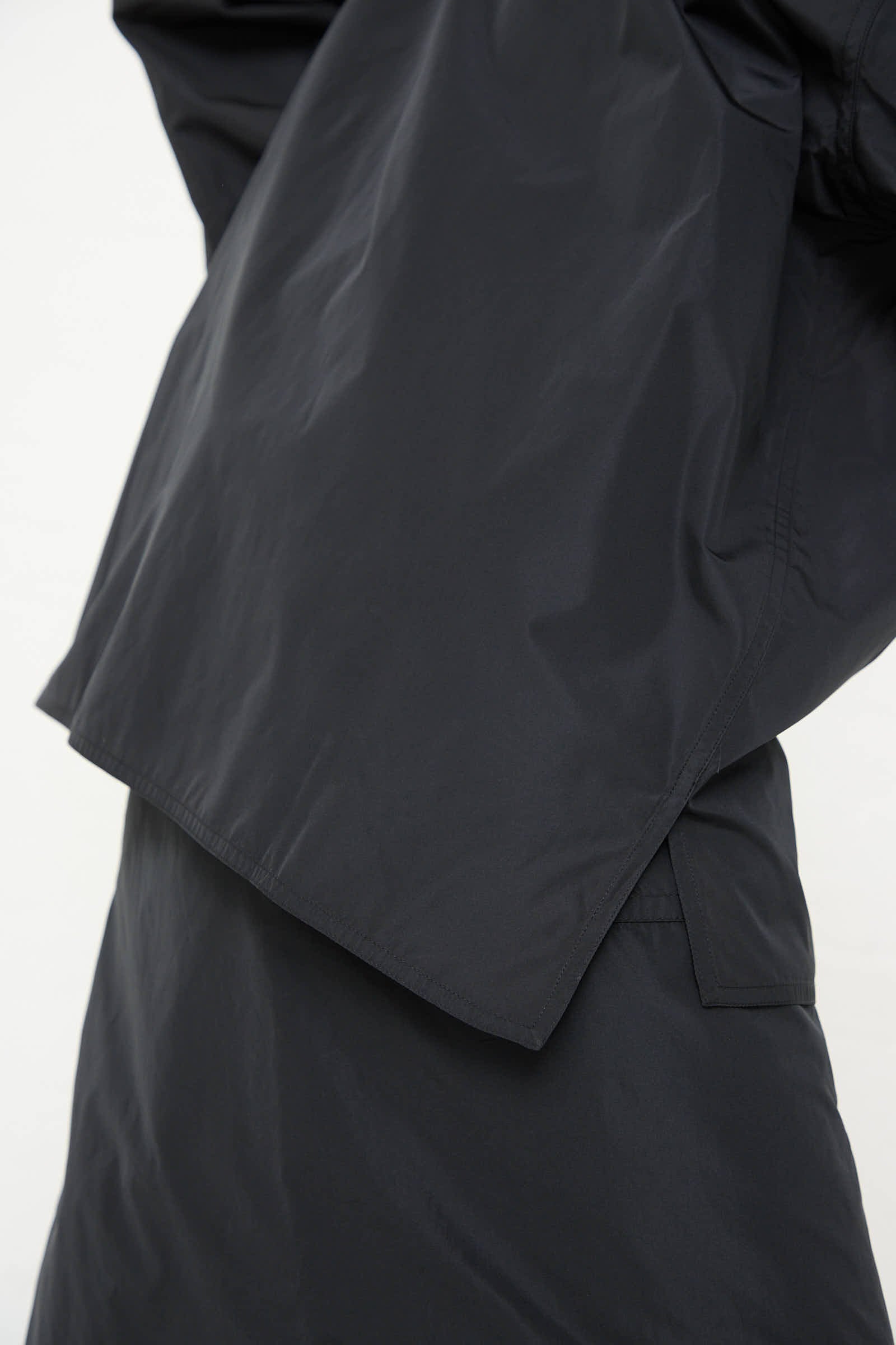 Close-up of a person's sleeve and part of the body, showcasing the detail and texture of the lightweight polyester fabric of the Taffeta Barry Shirt with Patch Pocket in Black by Sofie D'Hoore.