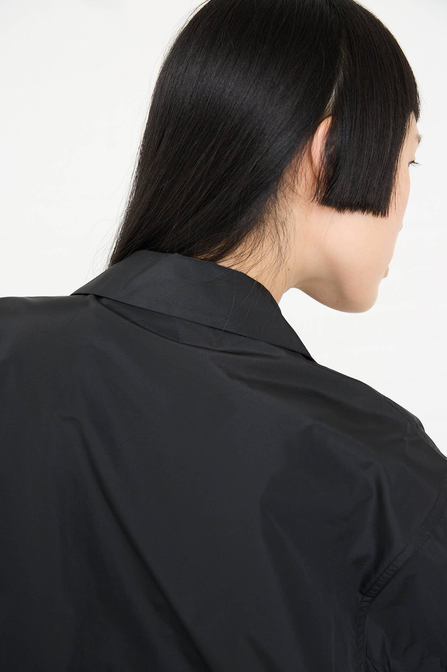 Back view of a person with straight black hair wearing a Taffeta Barry Shirt with Patch Pocket in Black by Sofie D'Hoore.