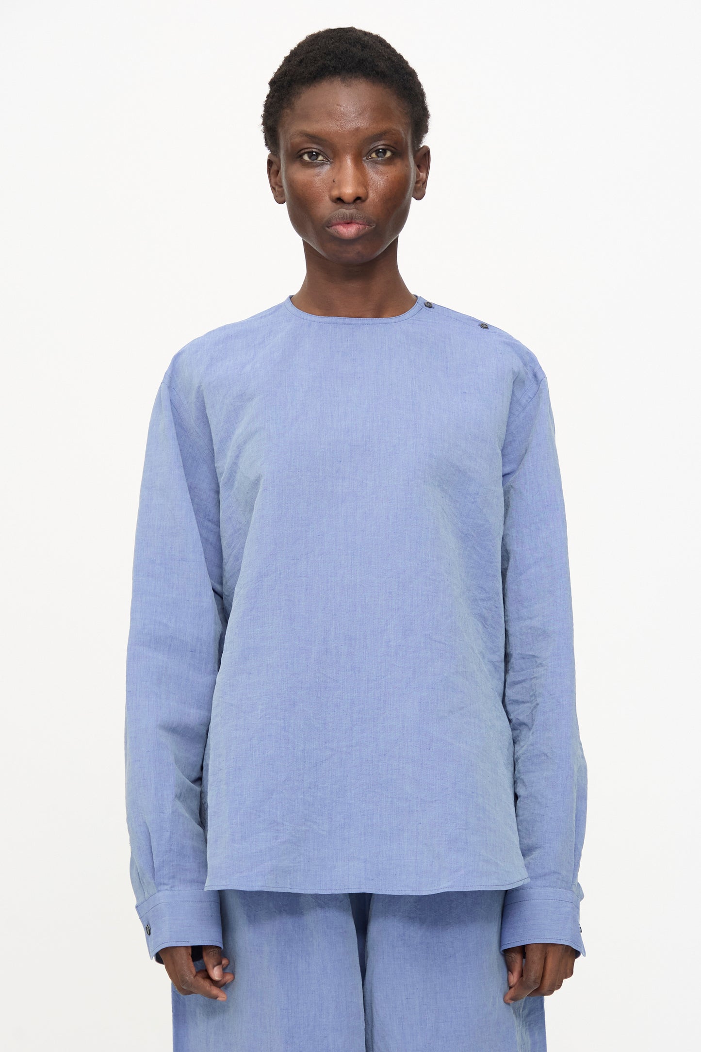 A person stands against a plain white background wearing the Sofie D'Hoore Barel Crewneck in Blue Jeans, paired with matching pants, looking directly at the camera with a neutral expression.