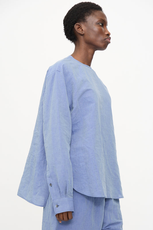 A person stands in profile wearing the Sofie D'Hoore Barel Crewneck in Blue Jeans, a relaxed-fit long sleeve shirt, paired with matching pants against a plain white background.