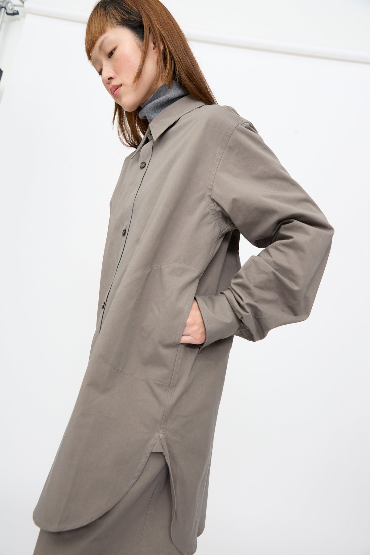 A person wearing a Sofie D’Hoore Brushed Cotton Voile Breg Shirt in Turtle, an oversized button-up in grey with a collar and side pocket.