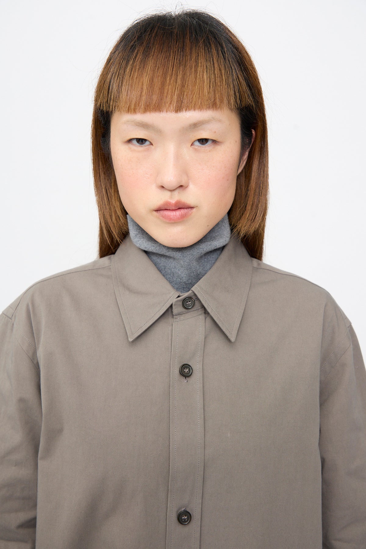 A person wearing a Sofie D’Hoore Brushed Cotton Voile Breg Shirt in Turtle over a grey turtleneck.