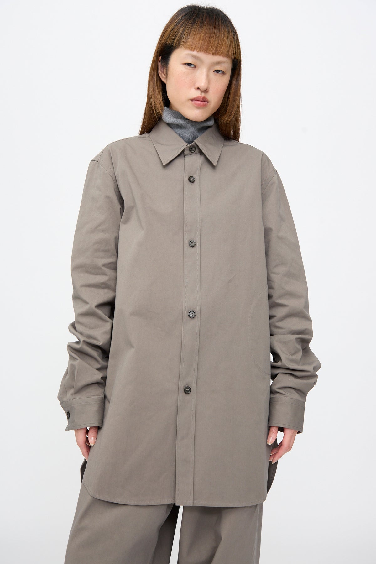 A person wearing a gray Sofie D’Hoore Brushed Cotton Voile Breg Shirt layered over a gray turtleneck.