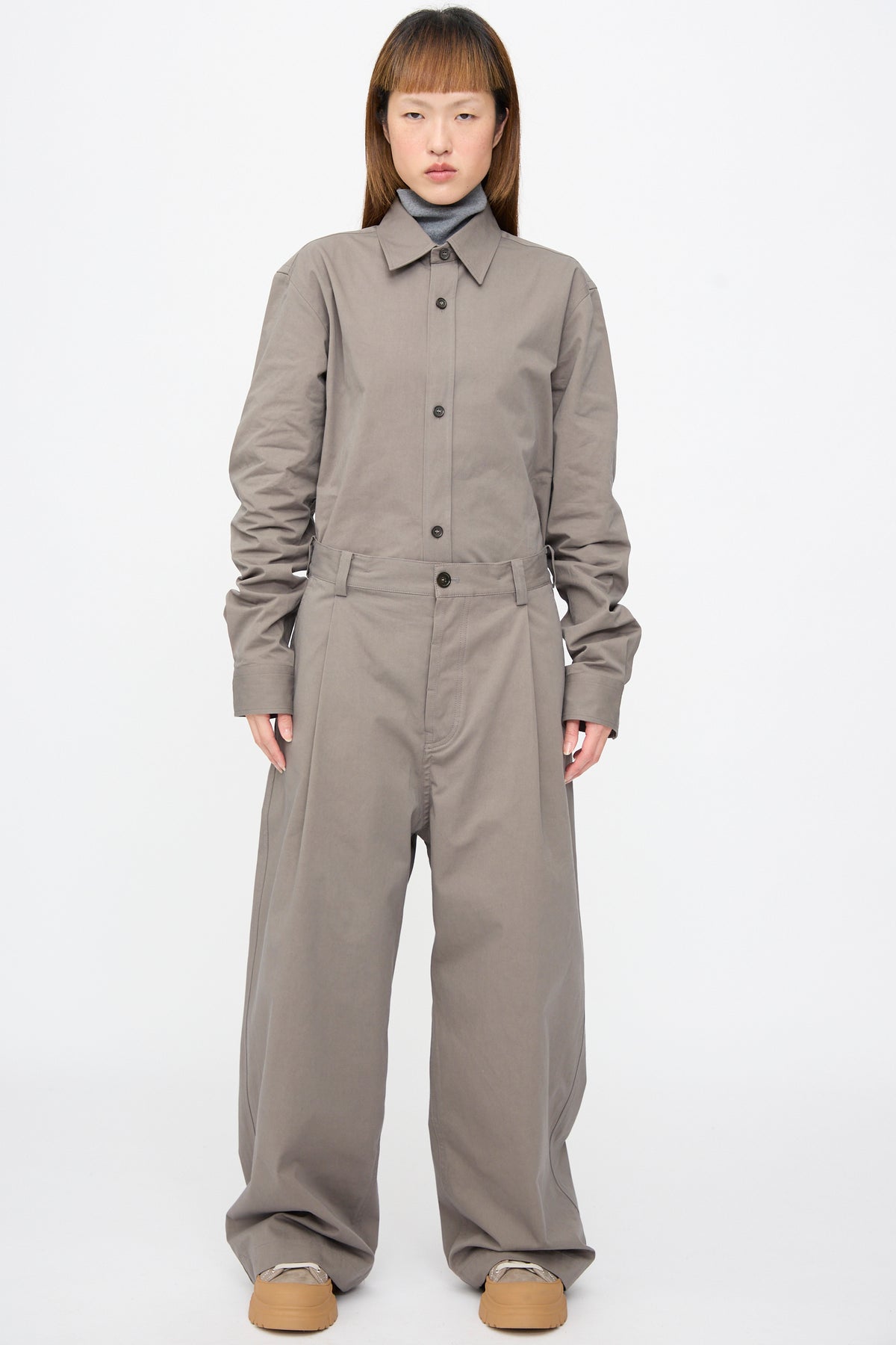 A person wearing a grey button-up shirt tucked into matching Compact Winter Cotton Pasadena Pant in Turtle, layered over a grey turtleneck.