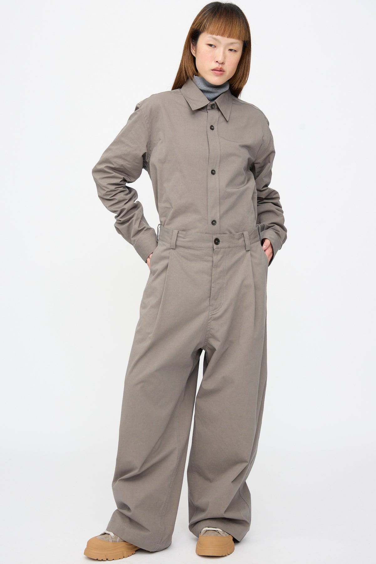 A person wears a grey turtleneck under a grey button-up shirt tucked into matching Compact Winter Cotton Pasadena Pant in Turtle, a relaxed-fit, wide-leg style.