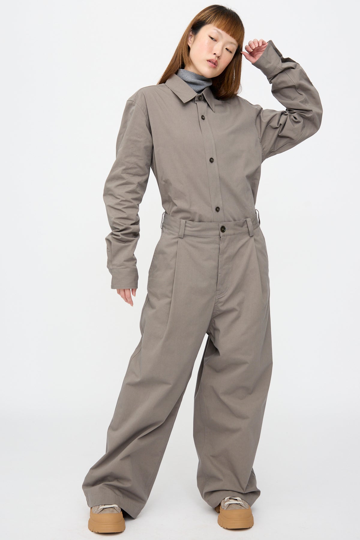 A person wearing a grey button-up shirt and a grey turtleneck tucked into matching Compact Winter Cotton Pasadena Pant in Turtle.