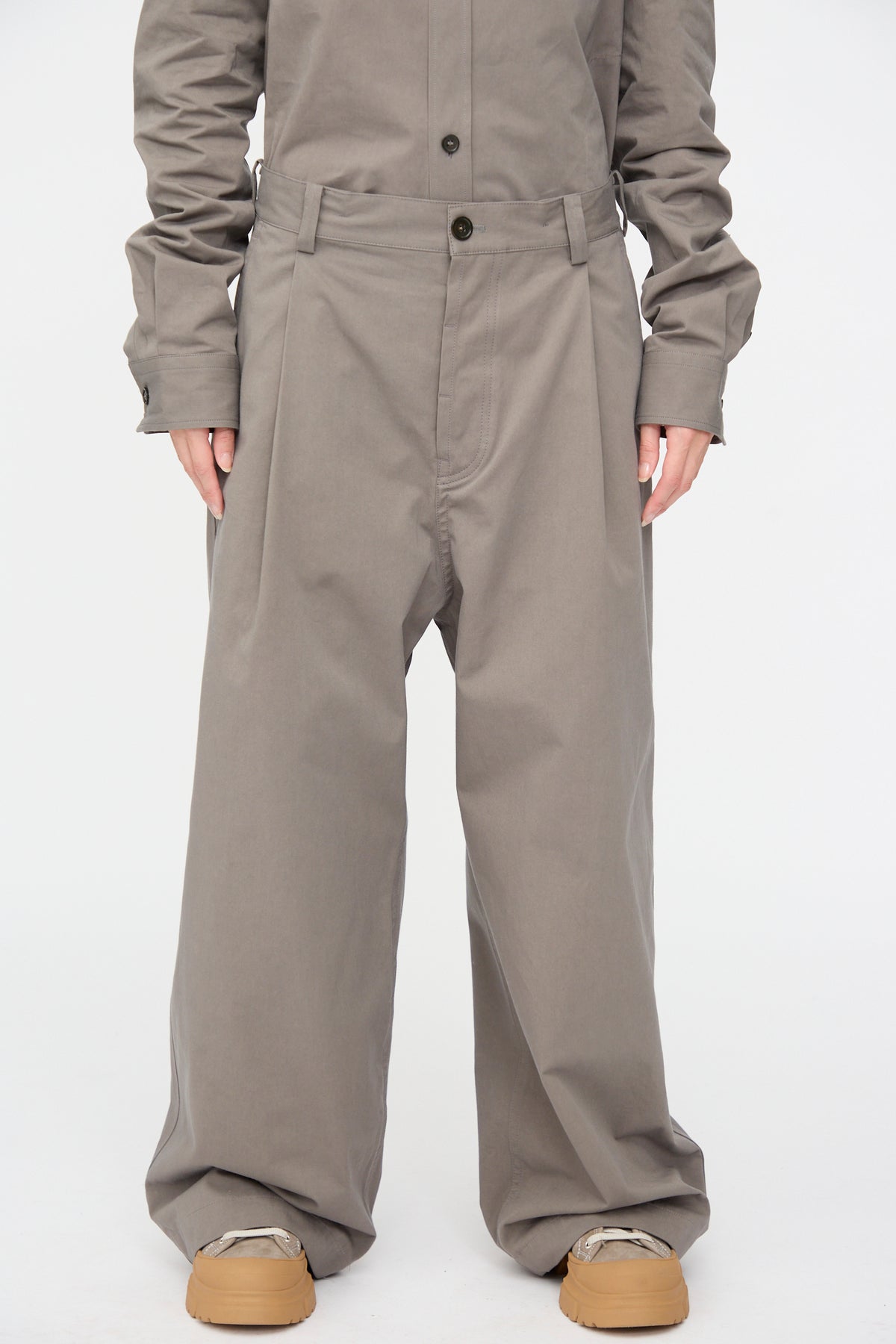 Relaxed-fit wide-leg Compact Winter Cotton Pasadena Pant in Turtle with front pleats, worn with a matching tucked-in shirt and thick-soled sneakers.