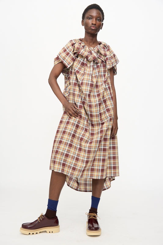 A person wears the Sofie D'Hoore Cotton Batiste Check Dolabella Dress in Toffee with navy socks and brown platform shoes, standing against a plain white background.