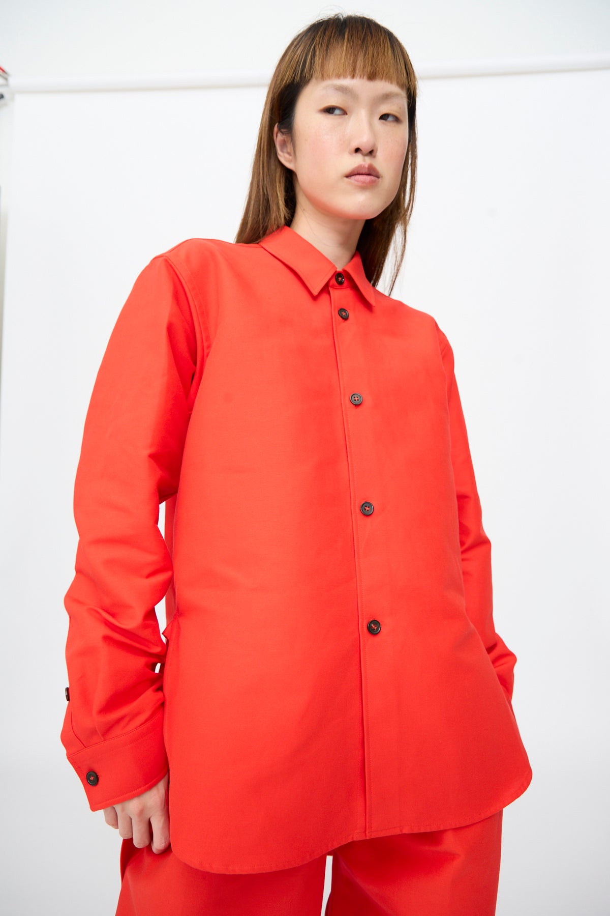 A bright red, oversized Cotton Duchesse Brant Shirt in Fire with a classic collar, long sleeves, and a hi-low hem.