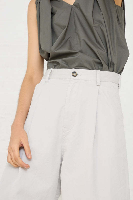 A woman wearing a grey top and light stone grey Cotton Twill Proof Pant in Mastic with pleat detail from Sofie D'Hoore.