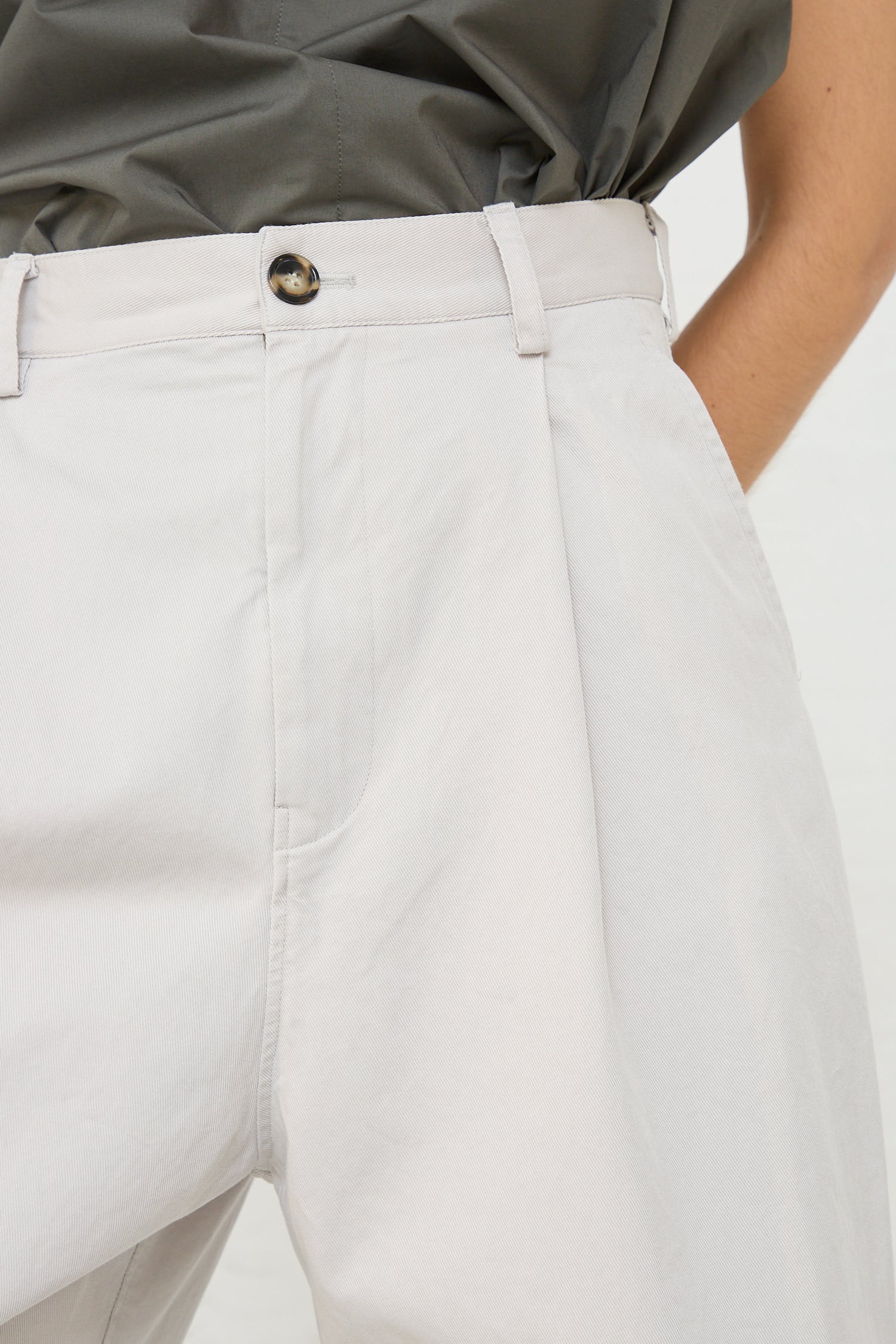 The back of a woman wearing a white shirt and low-rise pants in Sofie D'Hoore's Cotton Twill Proof Pant in Mastic.