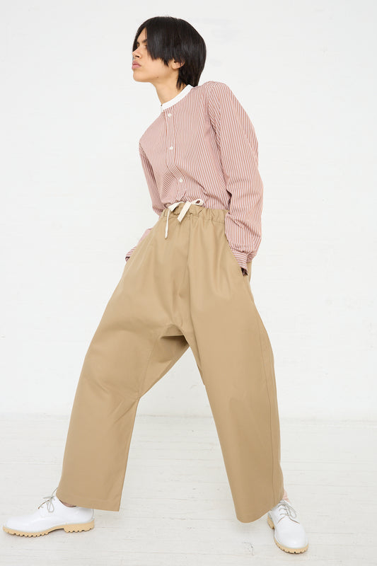 A woman wearing Sofie D'Hoore's Crisp Cotton Plof Pant in Dune colored wide leg pants and a cotton pink shirt.