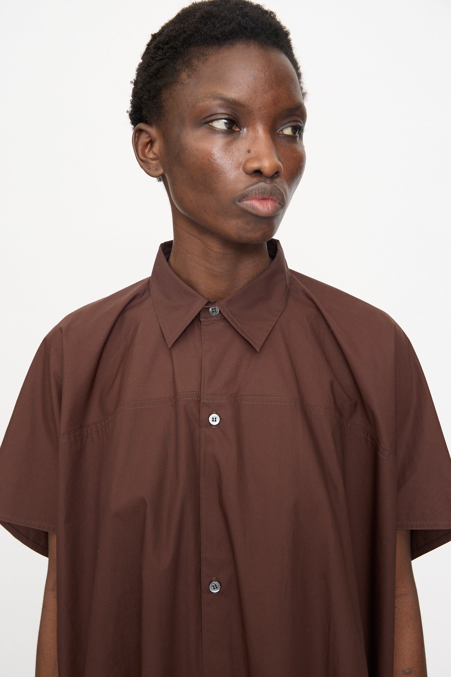 A person with short hair wears the Sofie D'Hoore Duchy Dress in Cacao and looks slightly to the side against a plain white background.